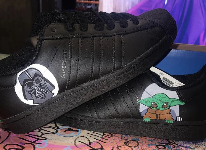 Pair of black sneakers with Star Wars character stickers: Darth Vader and Baby Yoda.