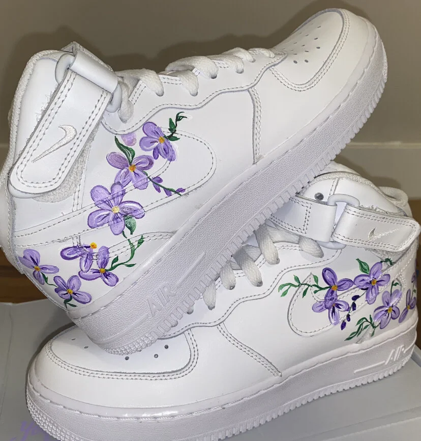 Pair of white sneakers with purple floral hand-painted designs on sides.