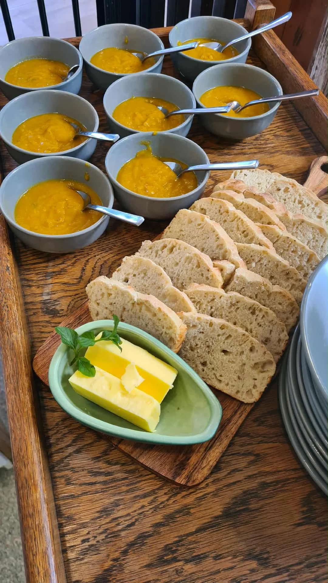 A bowl of assorted fresh fruits and snacks on a woven placemat, with a vase of pink flowers in the background.