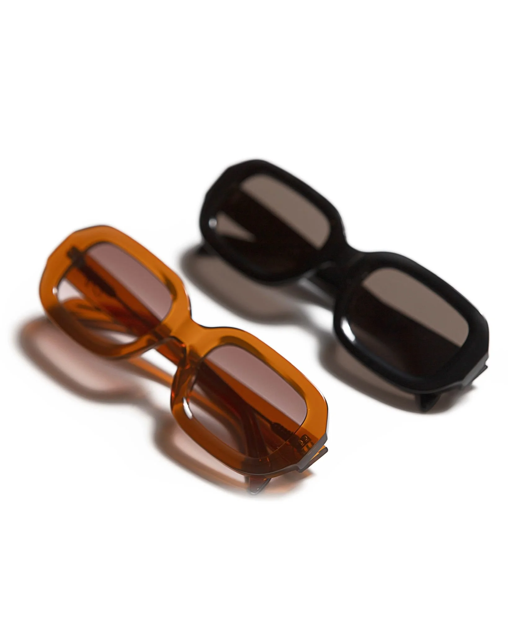 Two pairs of rectangular sunglasses, one with orange frames and the other with black frames, on a white background.