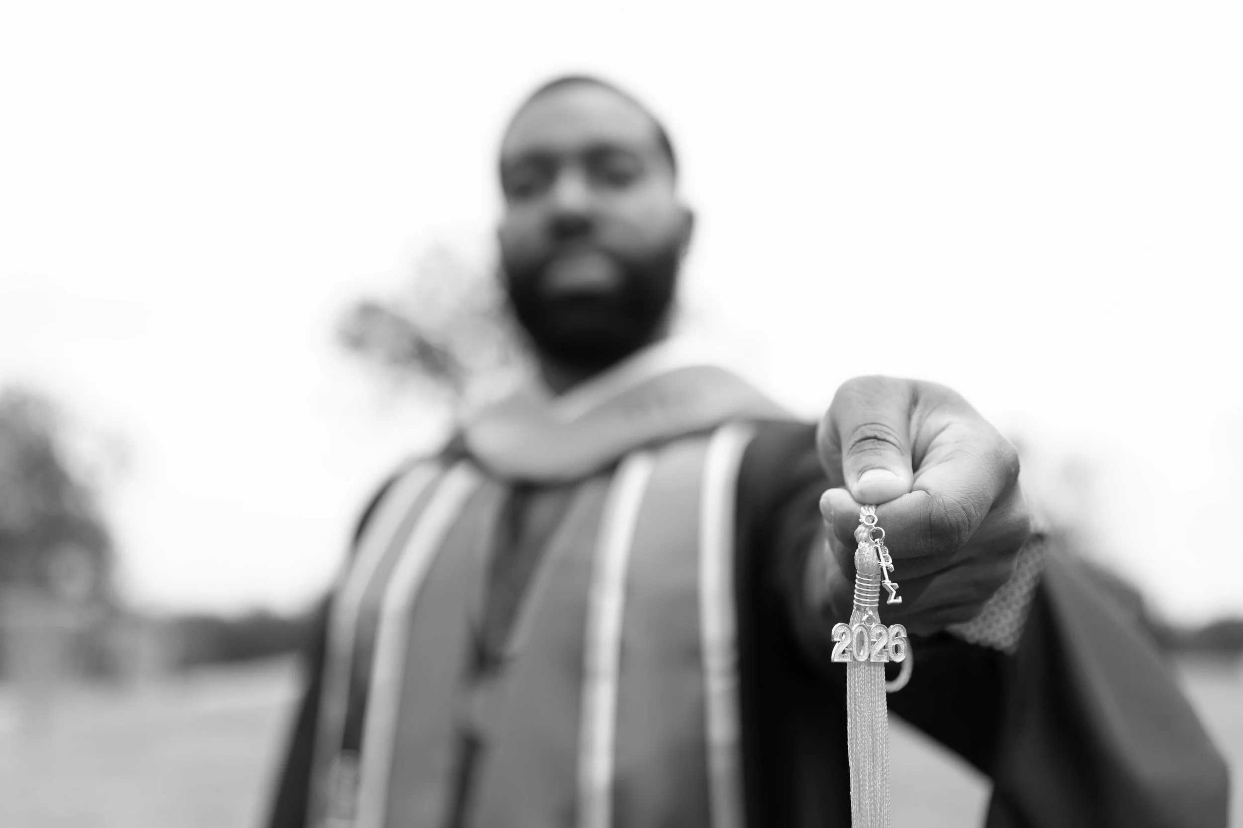 Close-up of a person holding a '2026' graduation tassel with a blurred face and background.