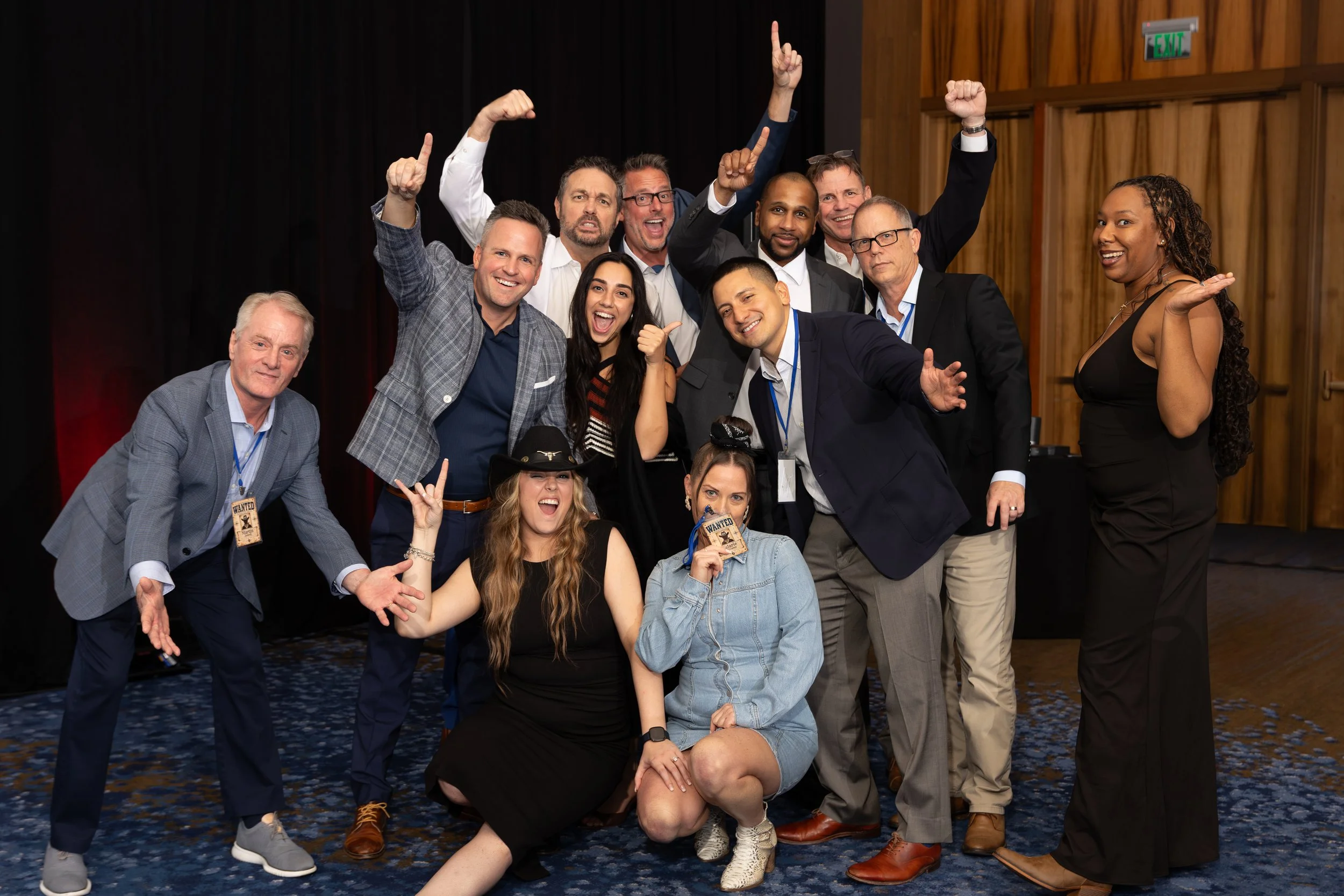 Group of smiling adults posing and celebrating together in a theater or event venue