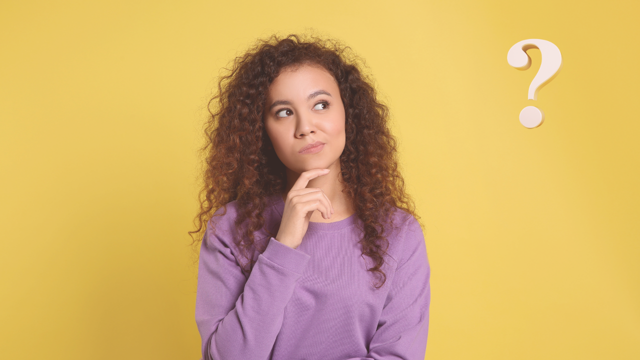 A young woman with curly hair wearing a purple sweater, looking thoughtful with her hand on her chin against a yellow background with a question mark.
