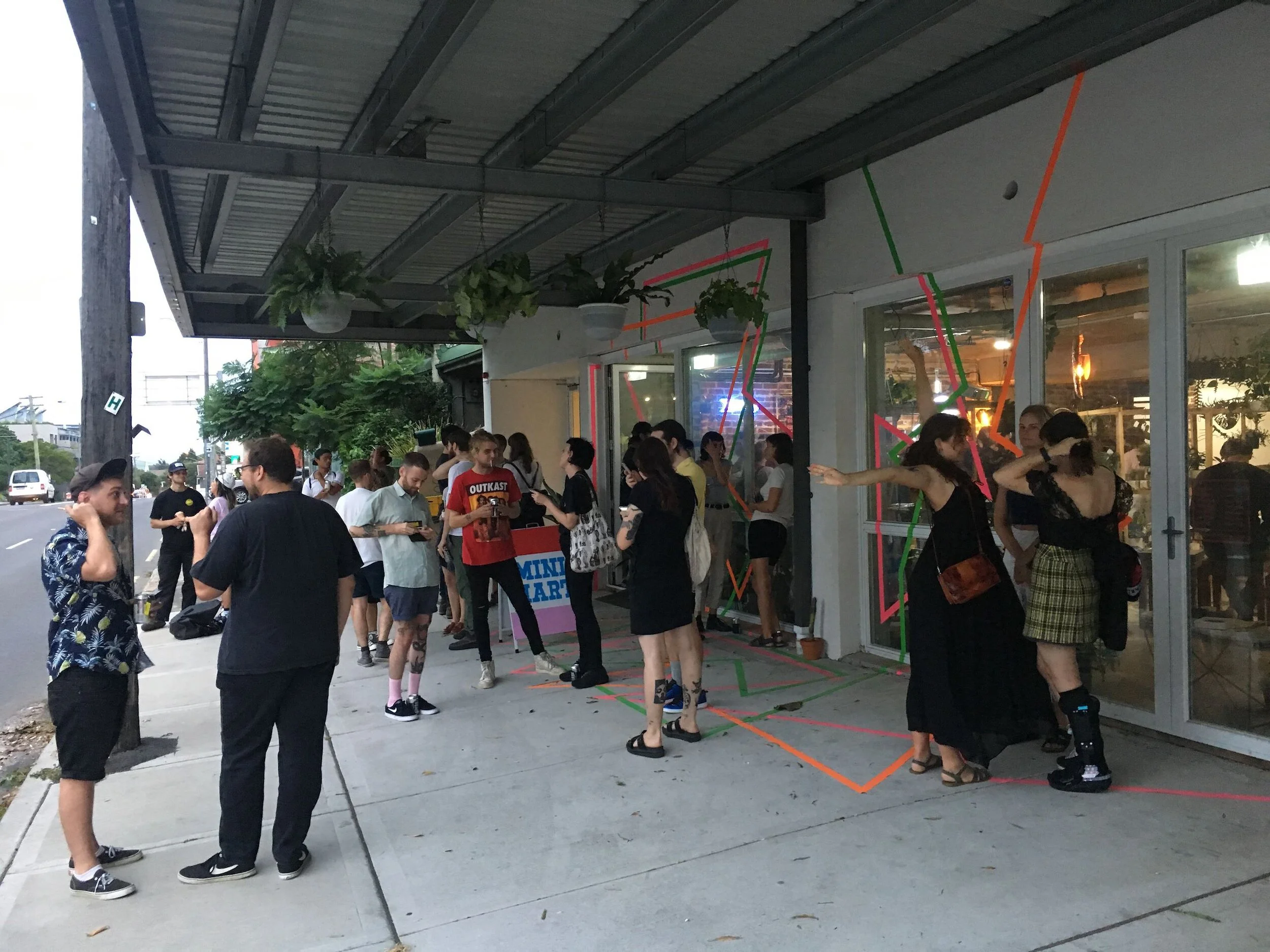 People waiting outside a store or restaurant with colorful neon line art decorations on the glass windows and door