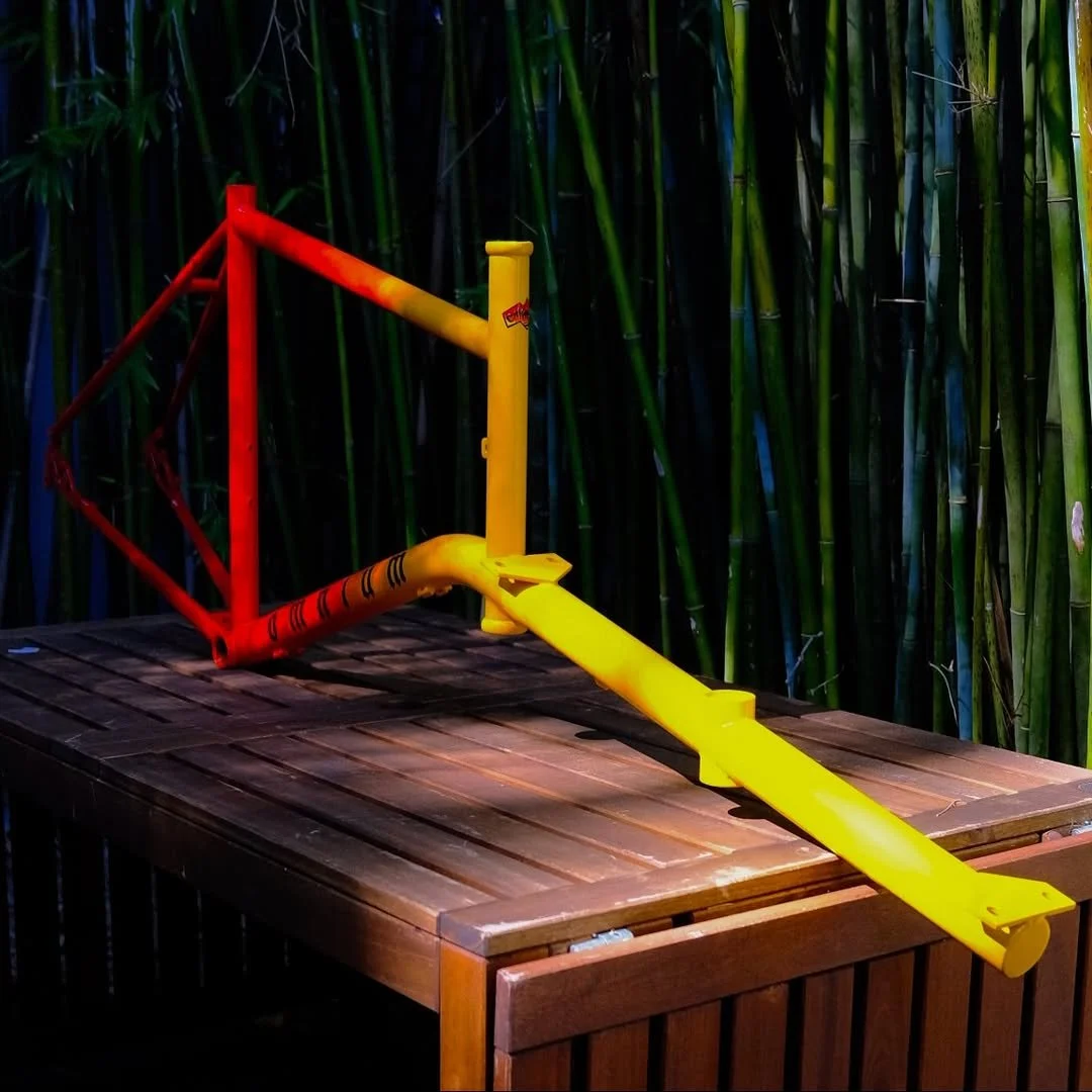 Yellow and red bicycle lane barrier with orange bars on a wooden table, surrounded by green bamboo plants.