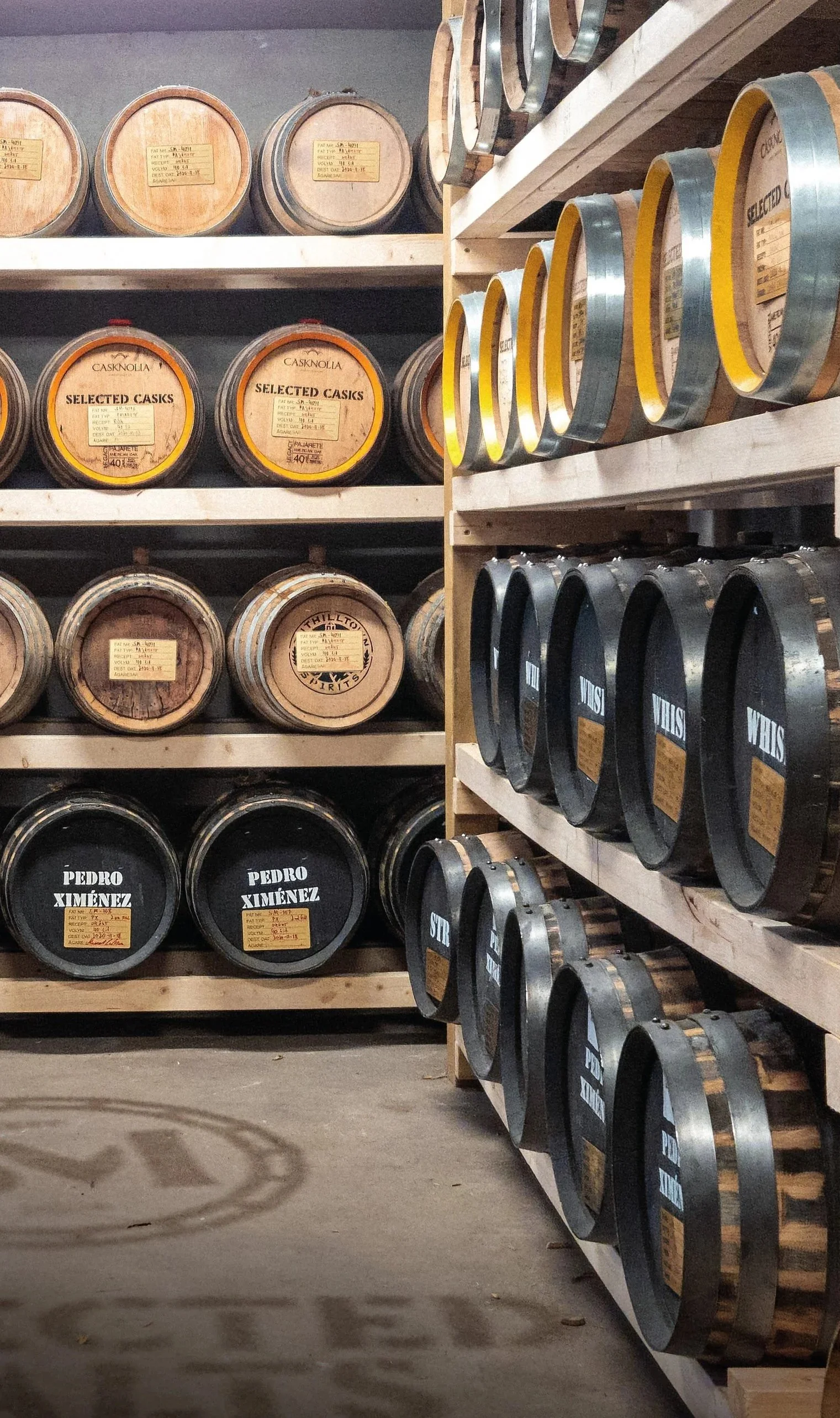 Rows of wooden barrels stored on shelves in a warehouse or cellar, used for aging spirits or wine.