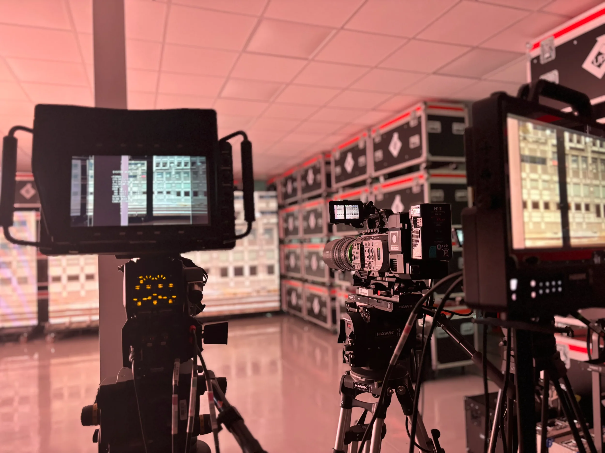 High-end video cameras with monitors and Hawk lenses set up inside a virtual production studio in front of ambient background LED video walls.