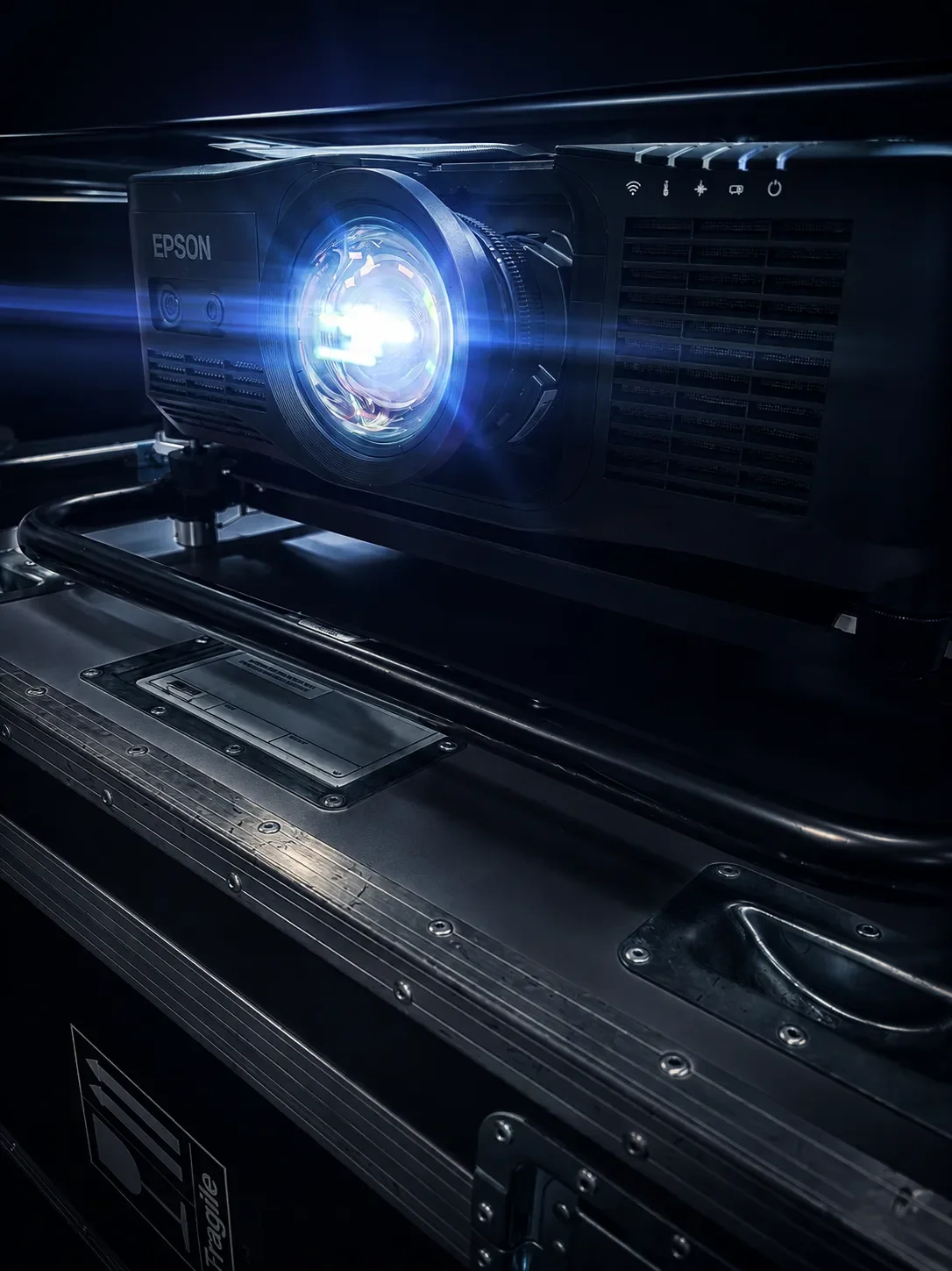 A close-up view of a high-brightness Epson professional projector mounted inside a protective rigging frame on an orange flight case.
