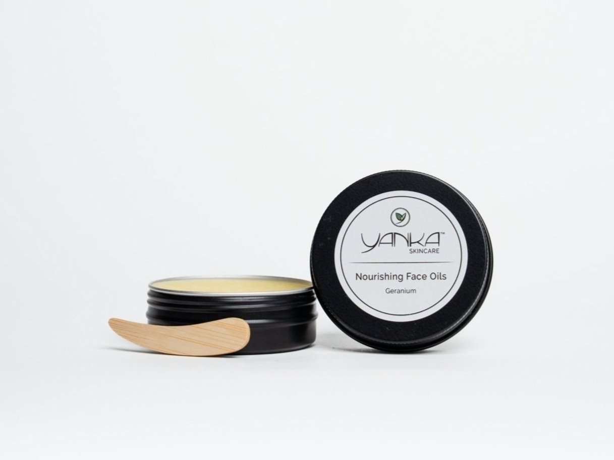 Yanka Skincare Nourishing Face Oils tin, open with balm inside and a wooden spatula, on a white background.