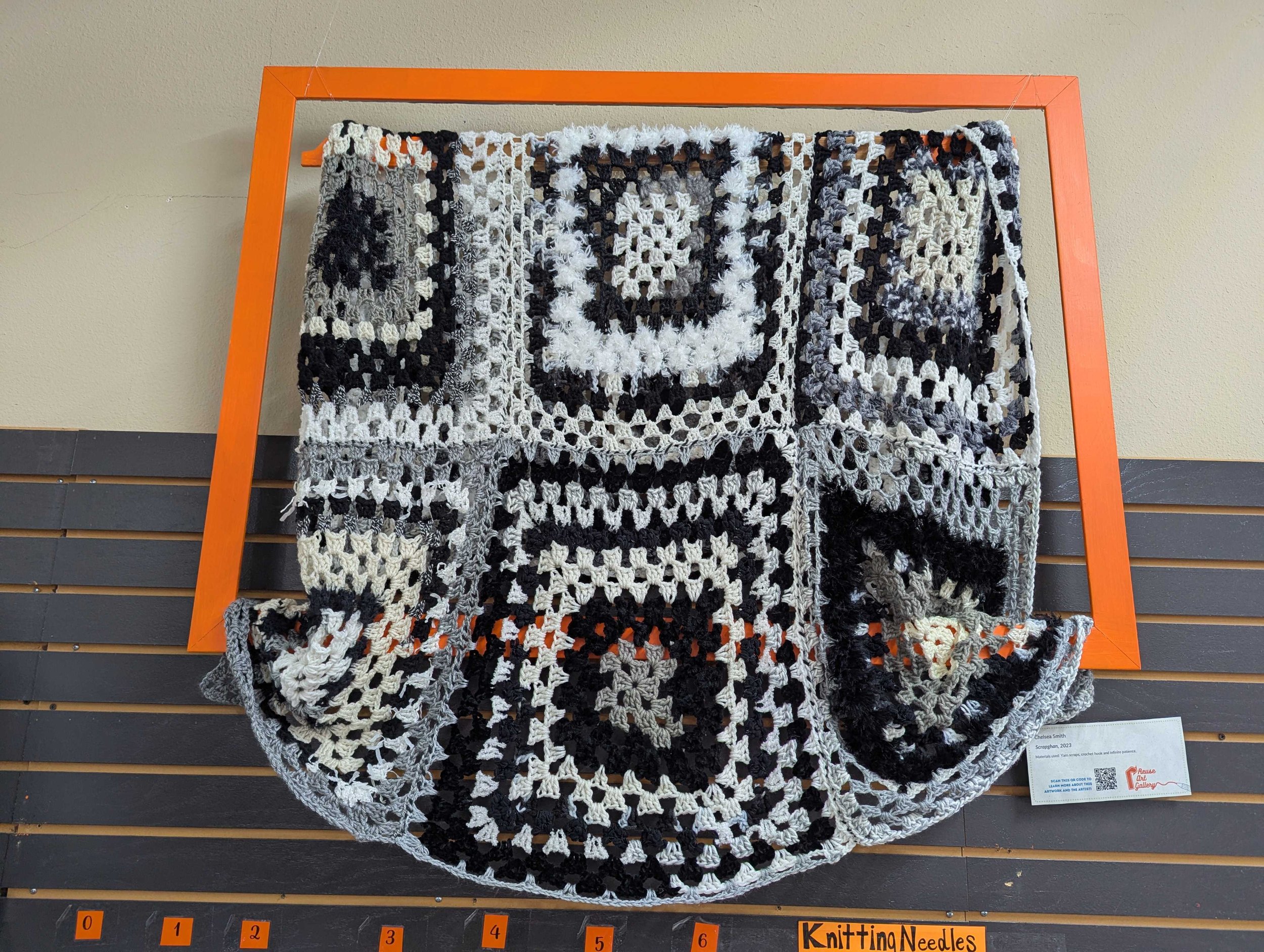 Black and white crochet blanket hanging in an orange frame