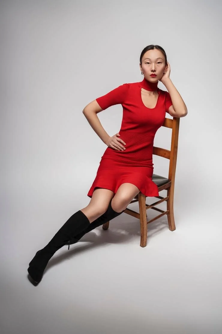 Mannequin femme en robe rouge assise, shooting en studio sur fond clair