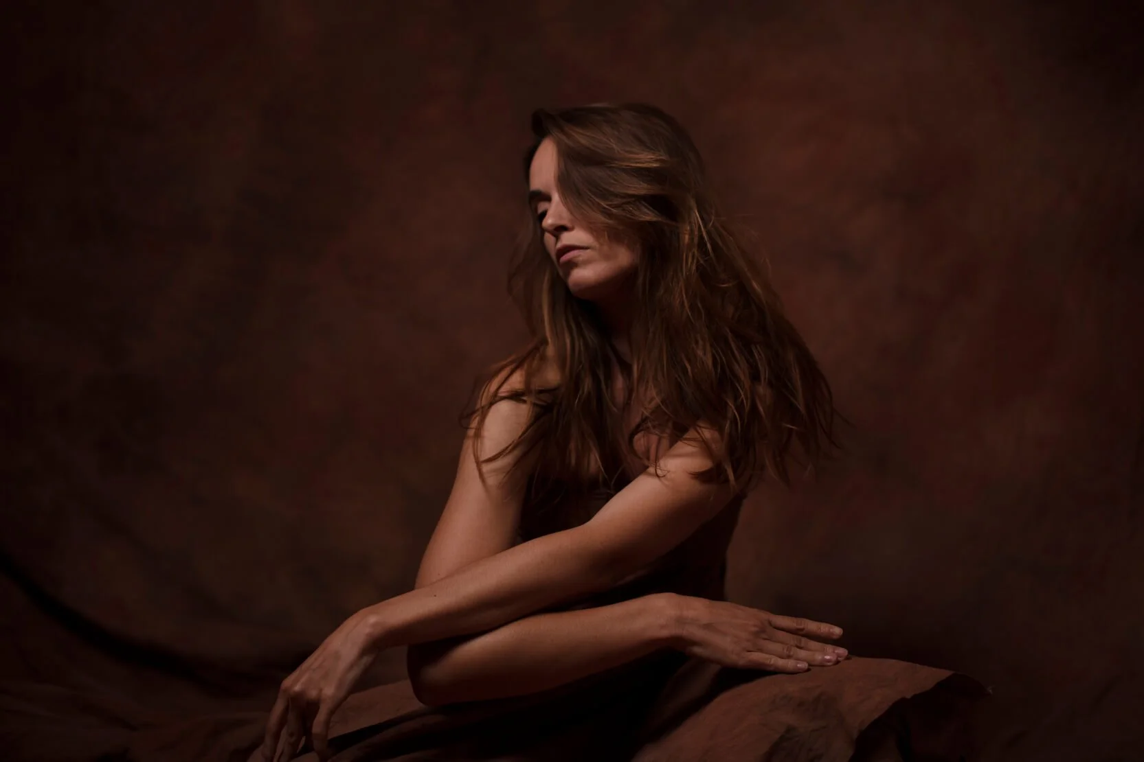 Mannequin femme assise, portrait éditorial en studio, lumière chaude sur fond peint