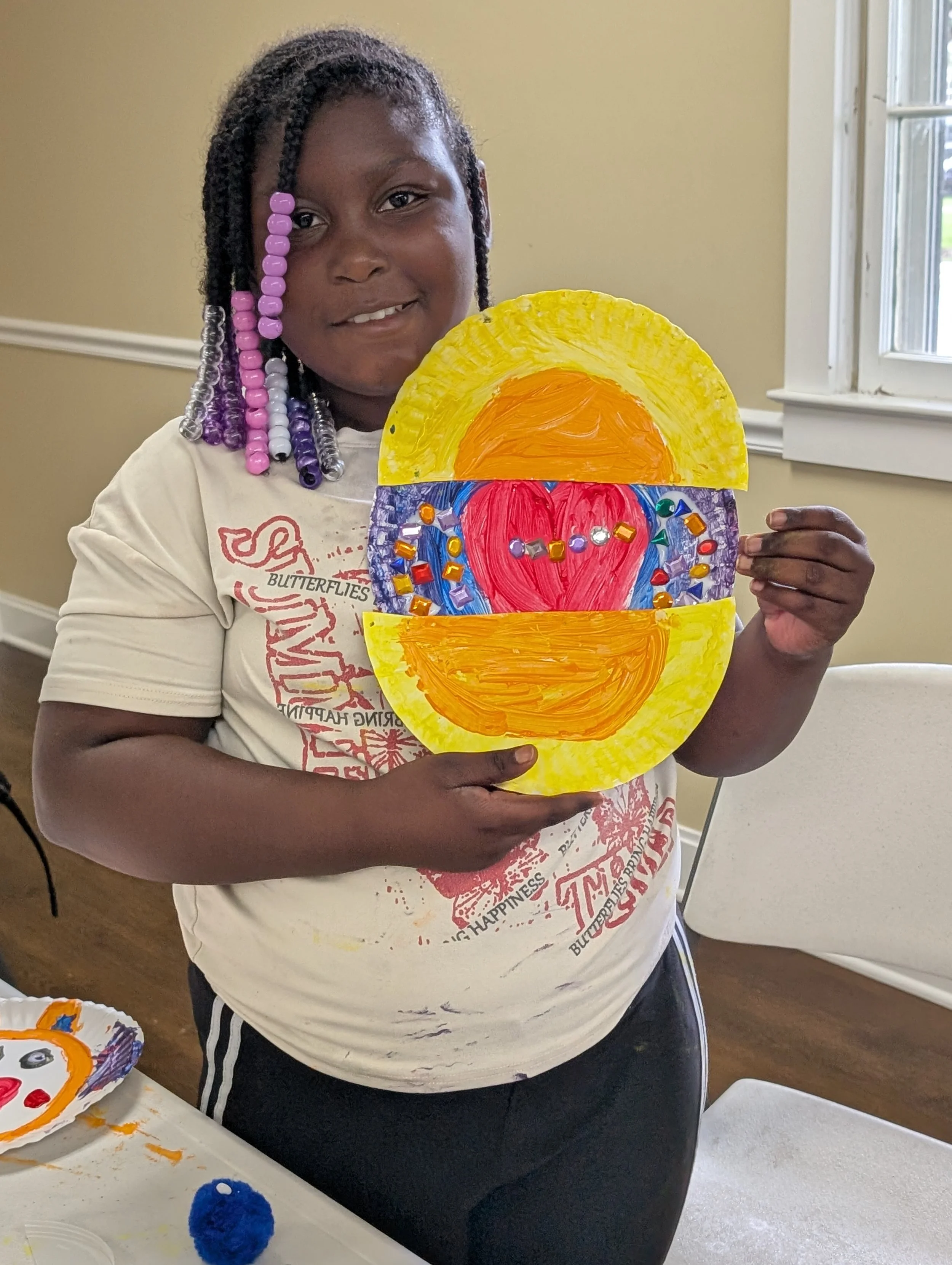 Girl holding up colorful art piece. 