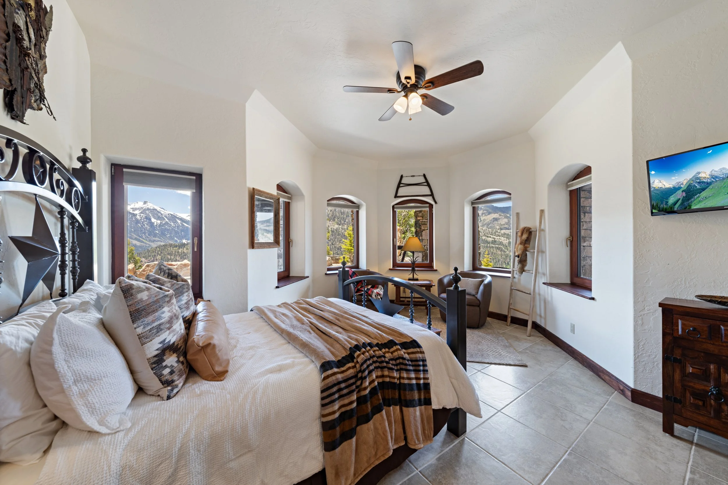 A cozy bedroom with a large bed, mountain views outside the windows, and rustic decor.