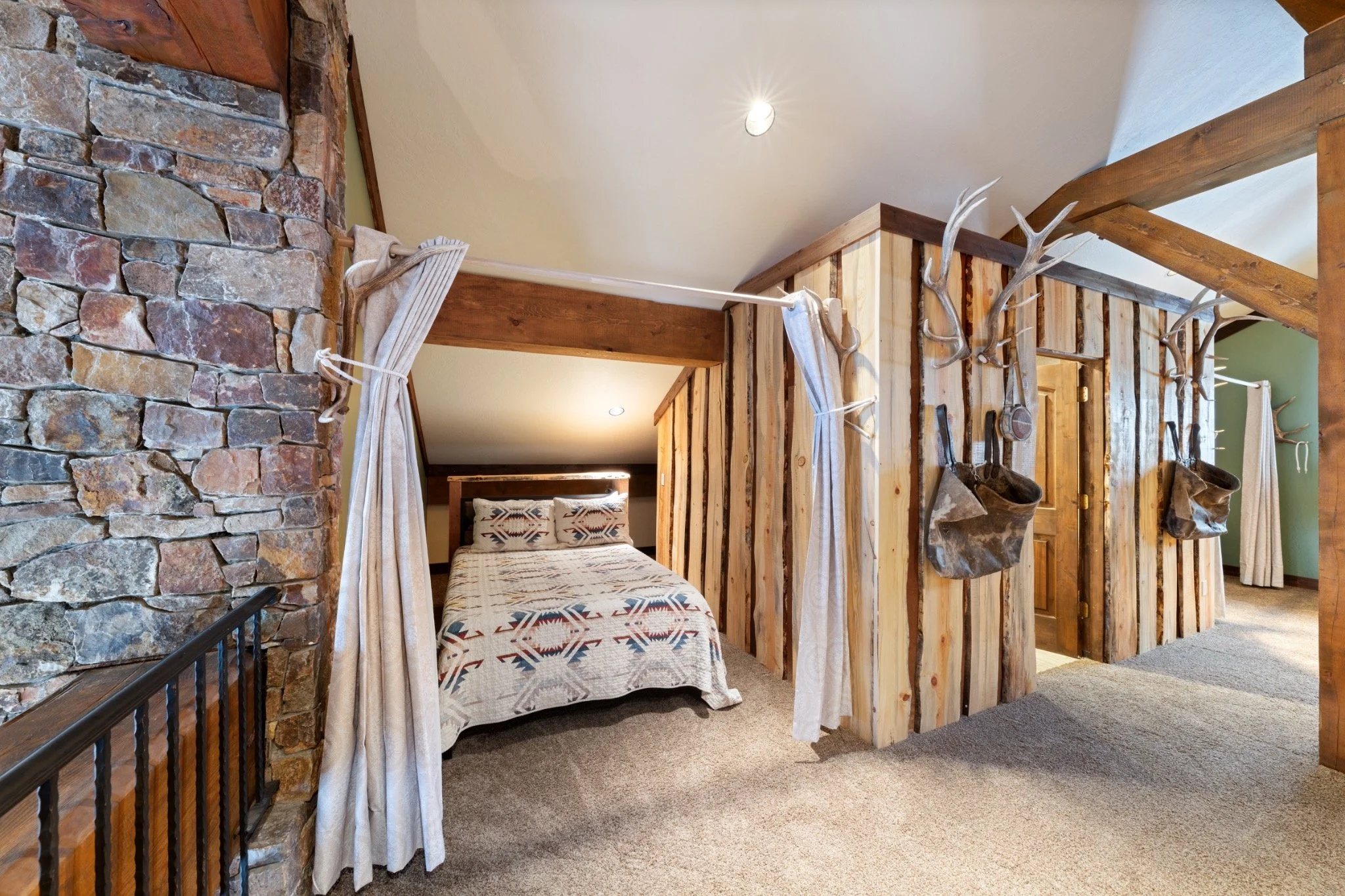 A rustic bedroom with a bed, wooden panel walls, and antler decorations.