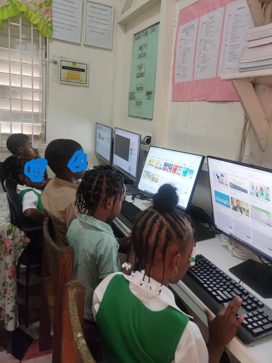 Children in a classroom using desktop computers for educational activities.