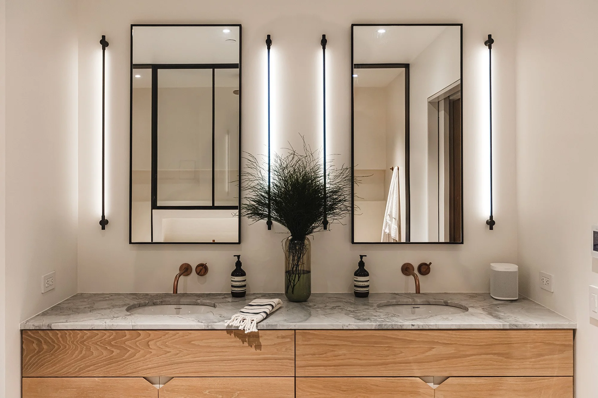 Bathroom vanity with superwhite stone vanity and thin sconces in Brooklyn