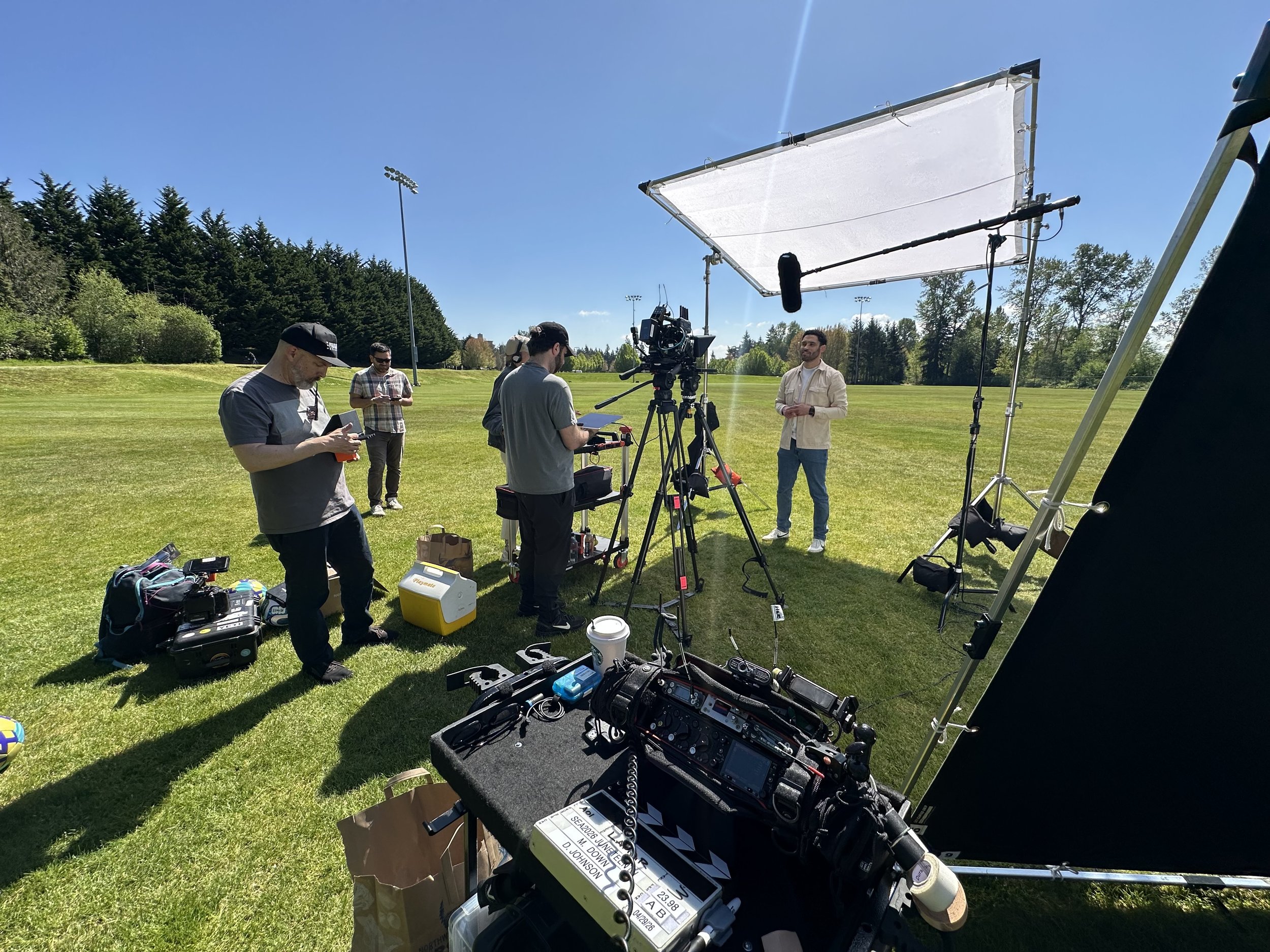 Kai Films crew filming an outdoor interview with cameras, lighting, and sound equipment.