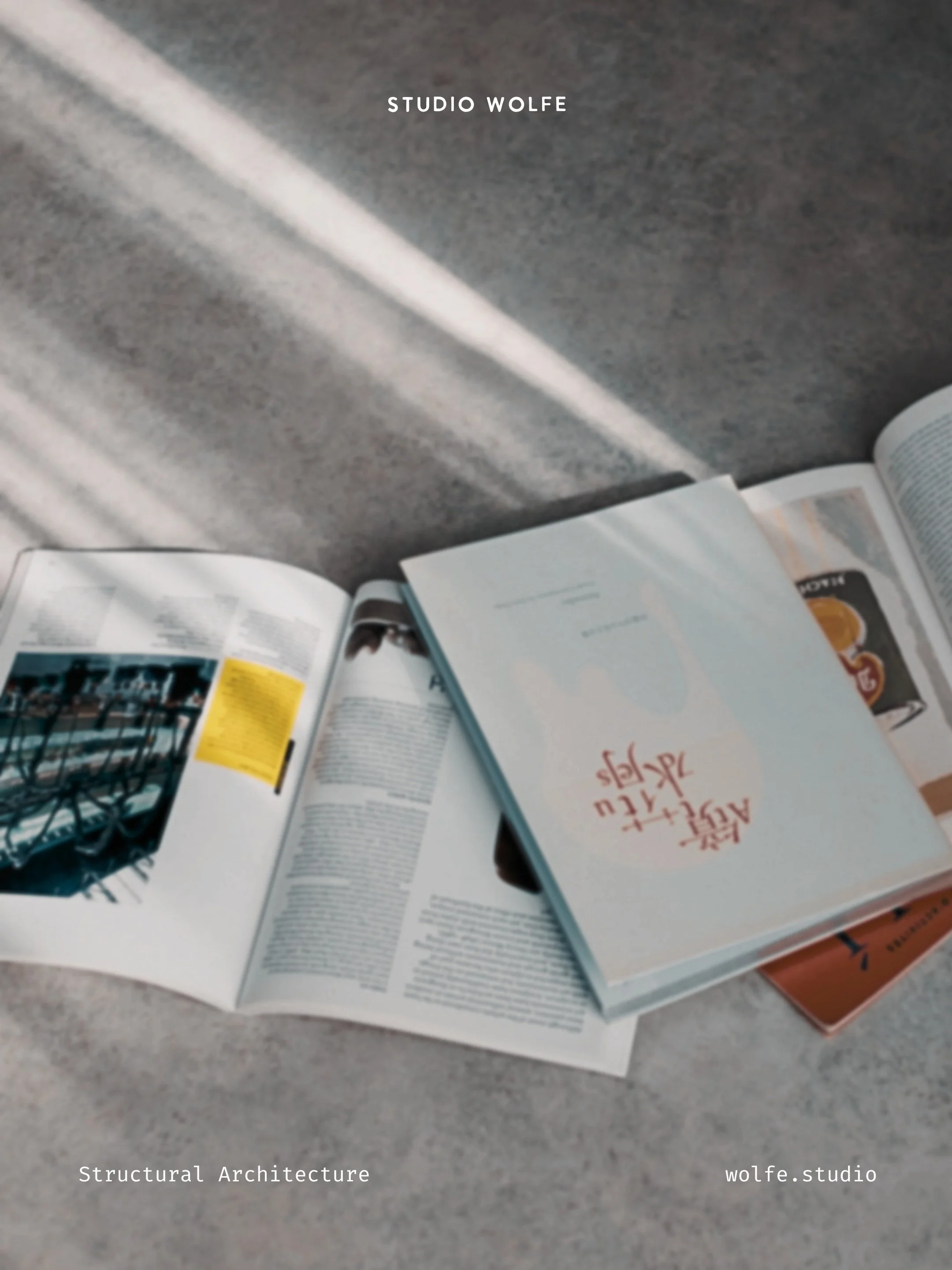 Open books and printed references arranged on a concrete floor, with soft diagonal light creating a quiet reading and research scene.