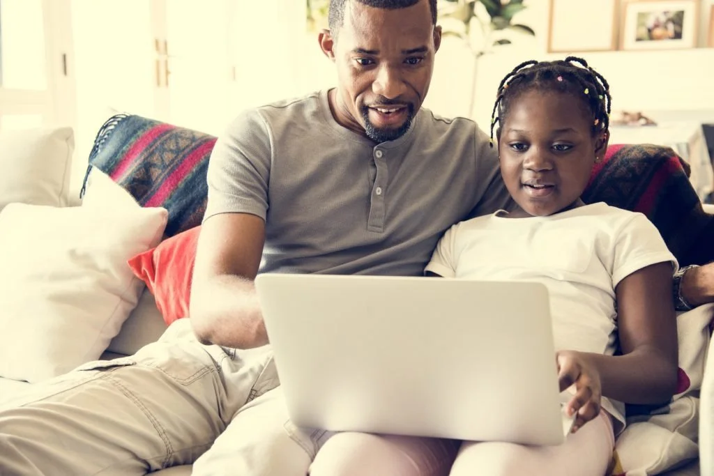 A Black man and his daughter comfortably listing in on a virtual panel