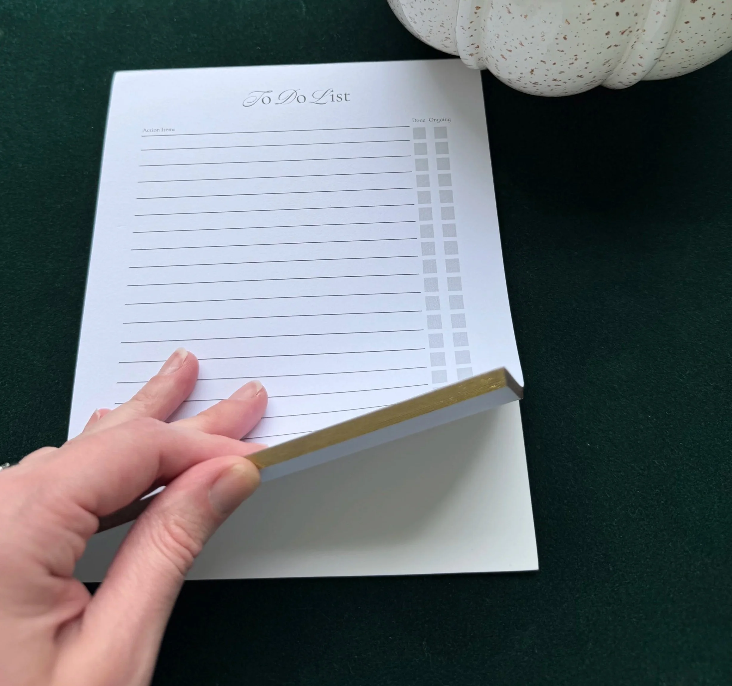 A person turns the pages of the gold edged notepad showing the gold edges