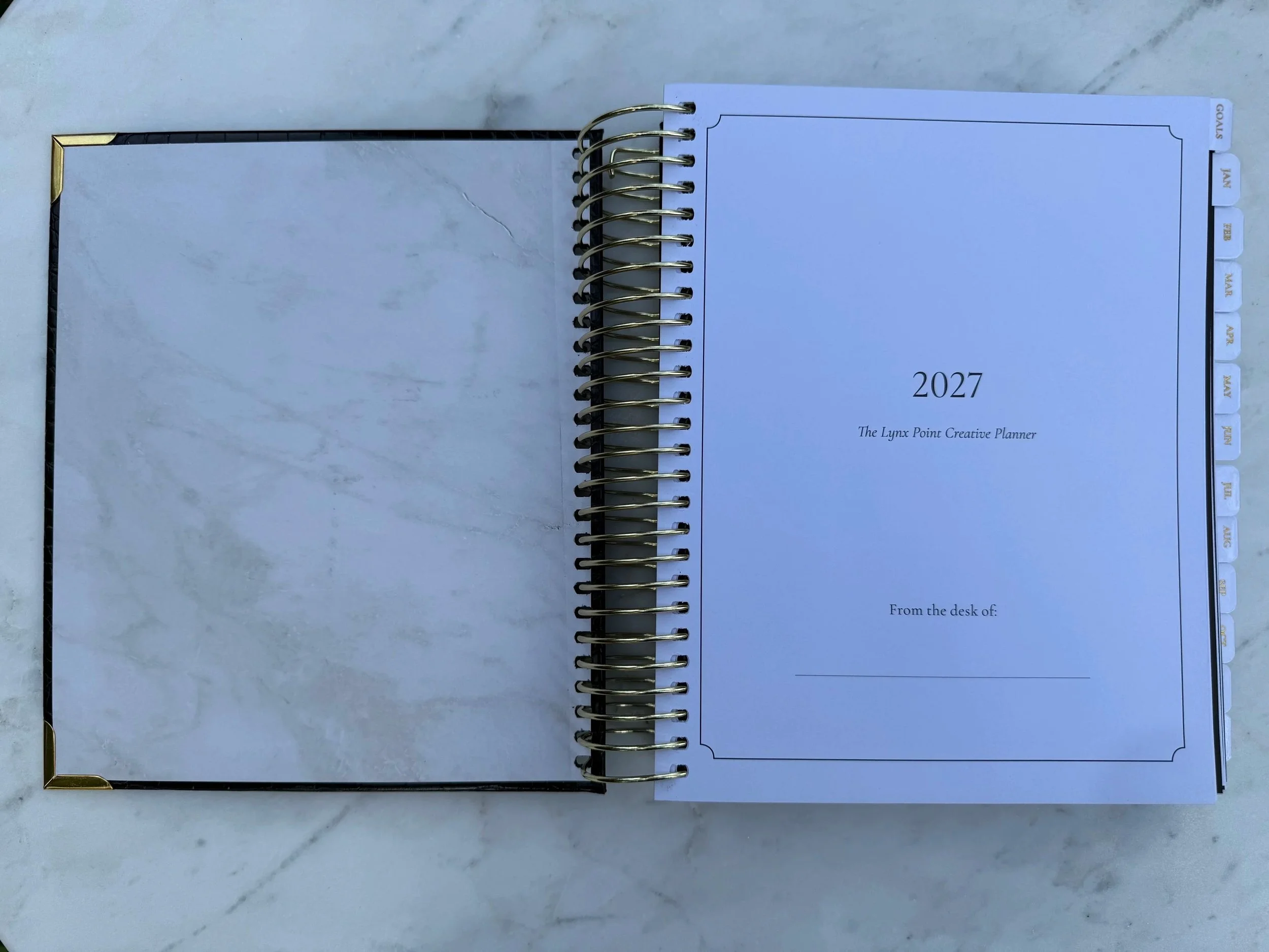 The front cover is opened of the Lynx Point Planner revealing marble ends paper and the first page