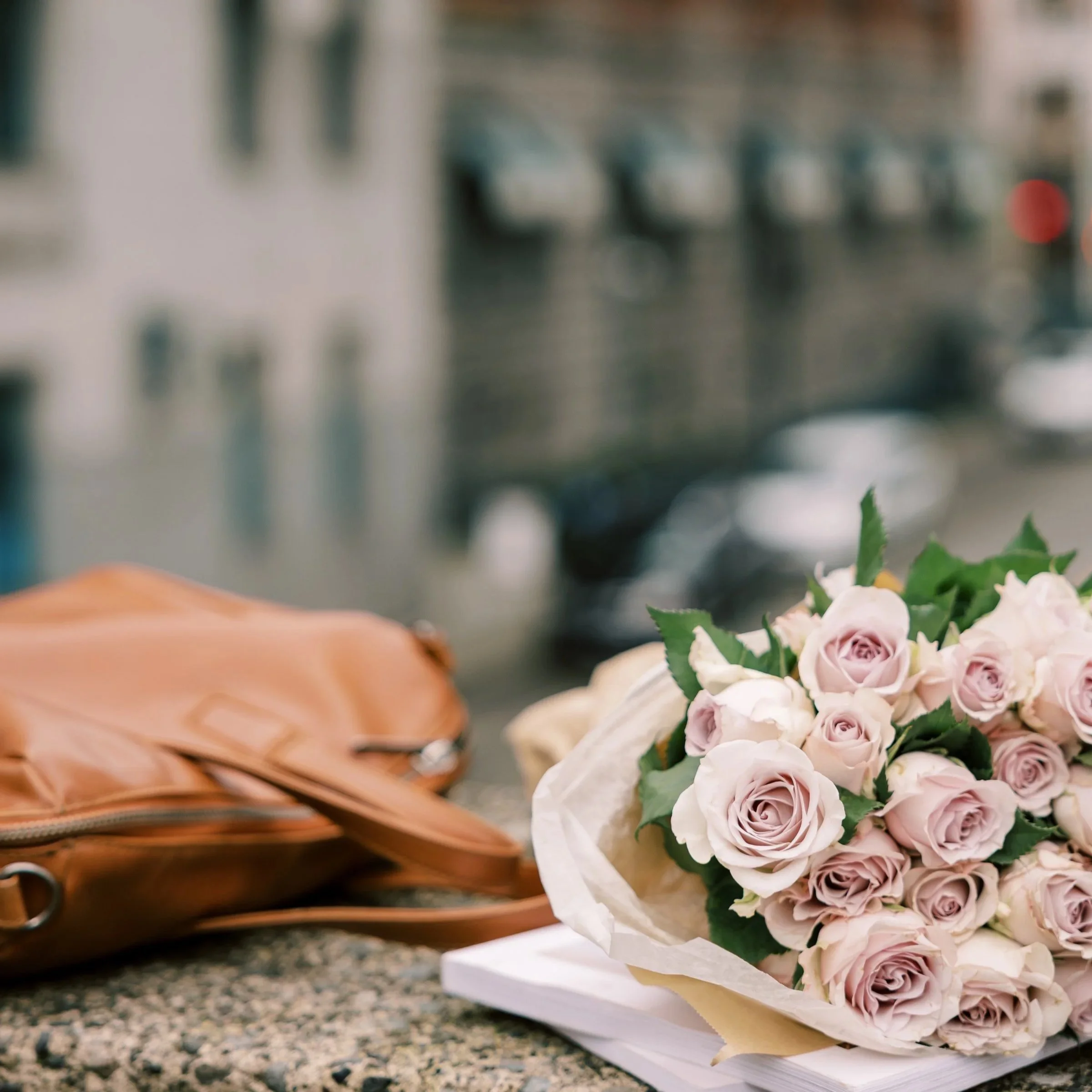 roses and a handbag on a wall overlooking city buildings