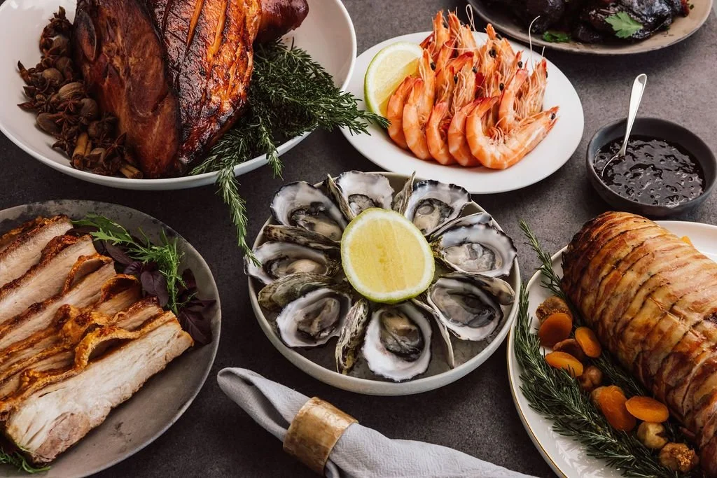 Business dinner spread including oysters, prawns, ham and more