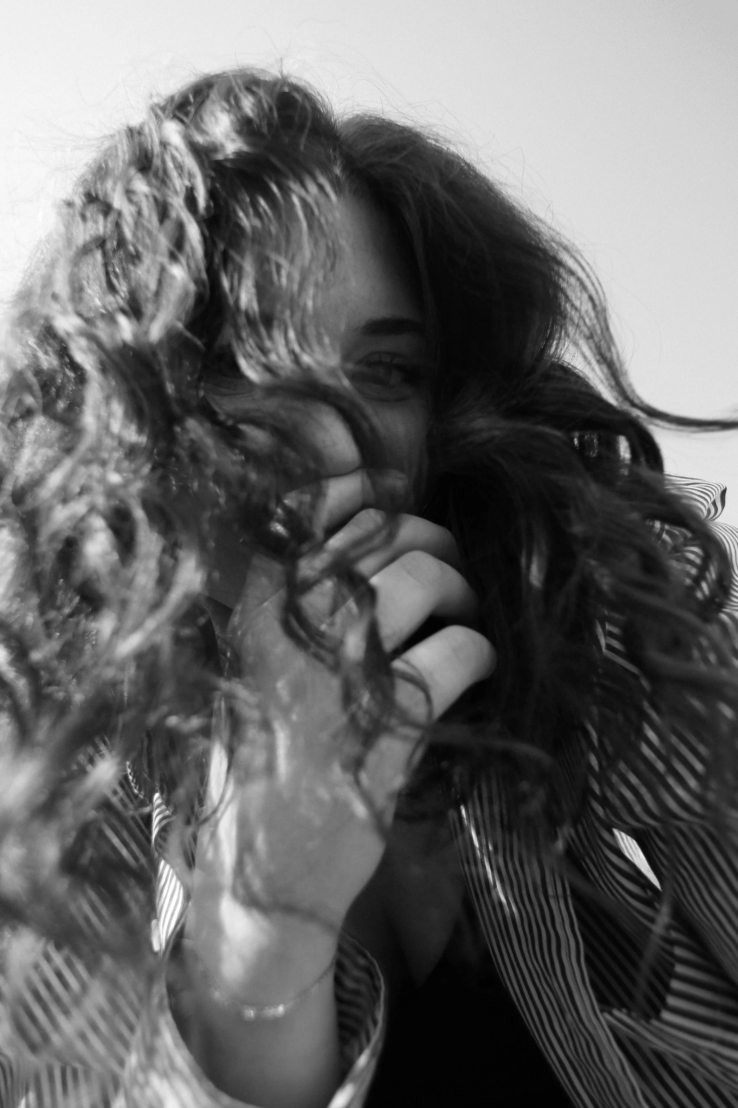 Claire Kantz press photo, black and white image of the wind blowing her hair in her face as she looks directly at the camera