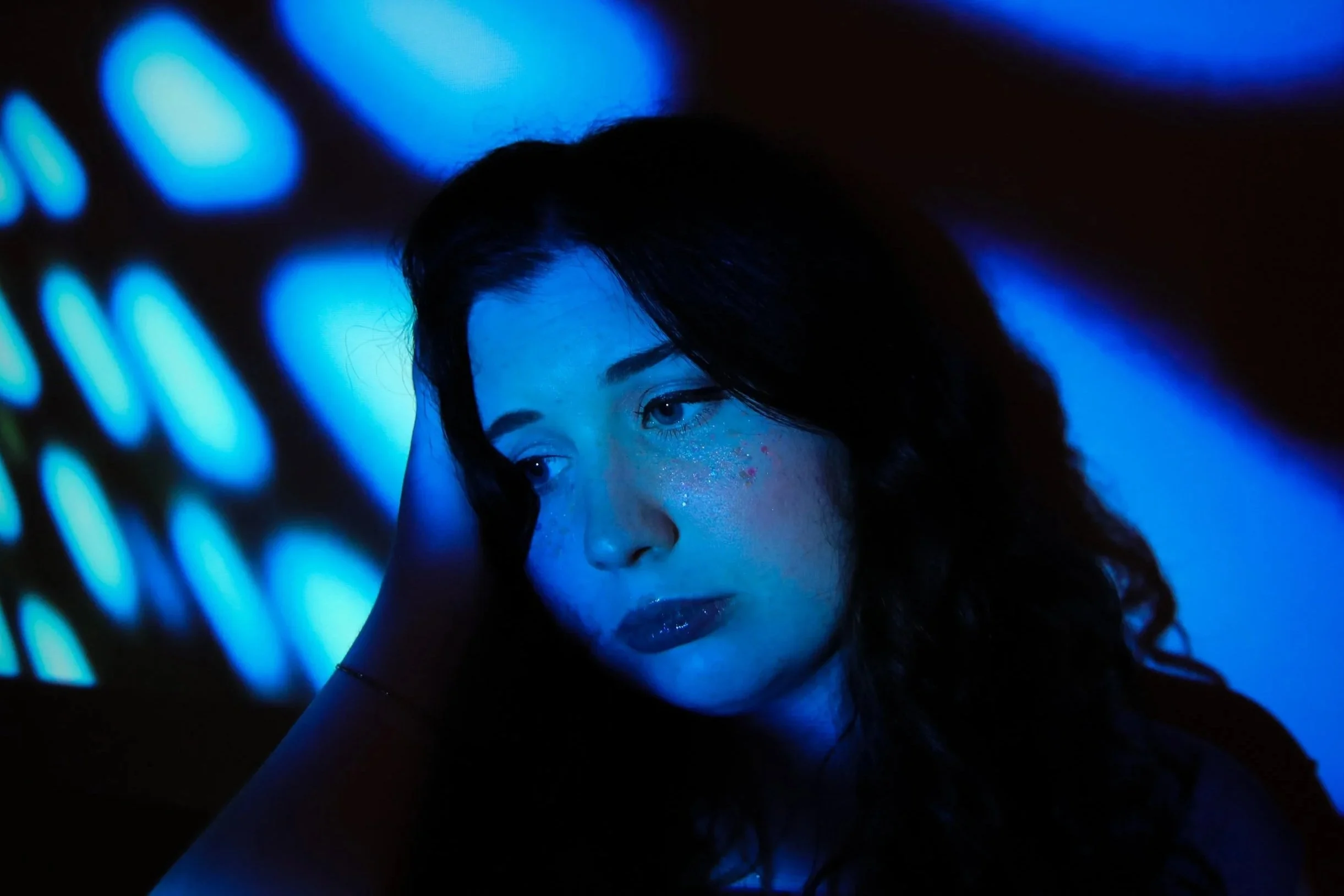 Claire Kantz press photo, looking away in blue projector light
