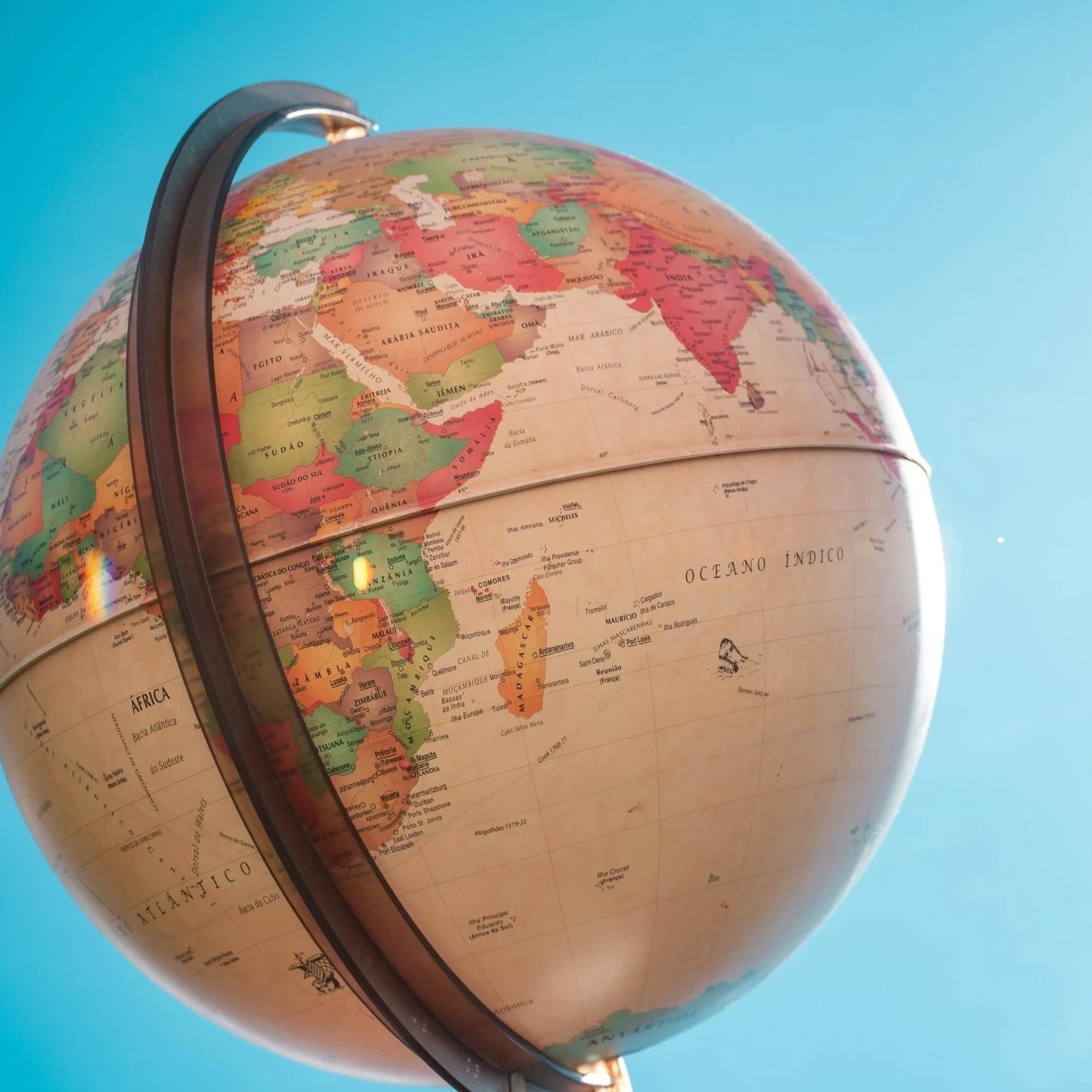 Un globe terrestre avec une orientation inclinée, montrant principalement l'Afrique et le Moyen-Orient à gauche et l'Asie et l'océan Indien à droite, contre un ciel bleu.