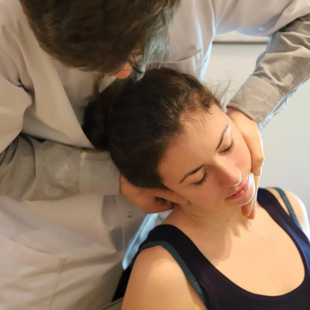 Une personne reçoit une séance de massage ou de thérapie du cou et du visage par un praticien. La personne est détendue et a les yeux fermés.