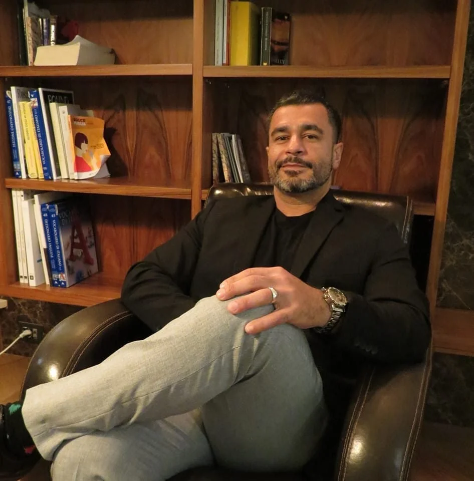 Miguel Ojeda smiling in leather office chair in front of a bookshelf