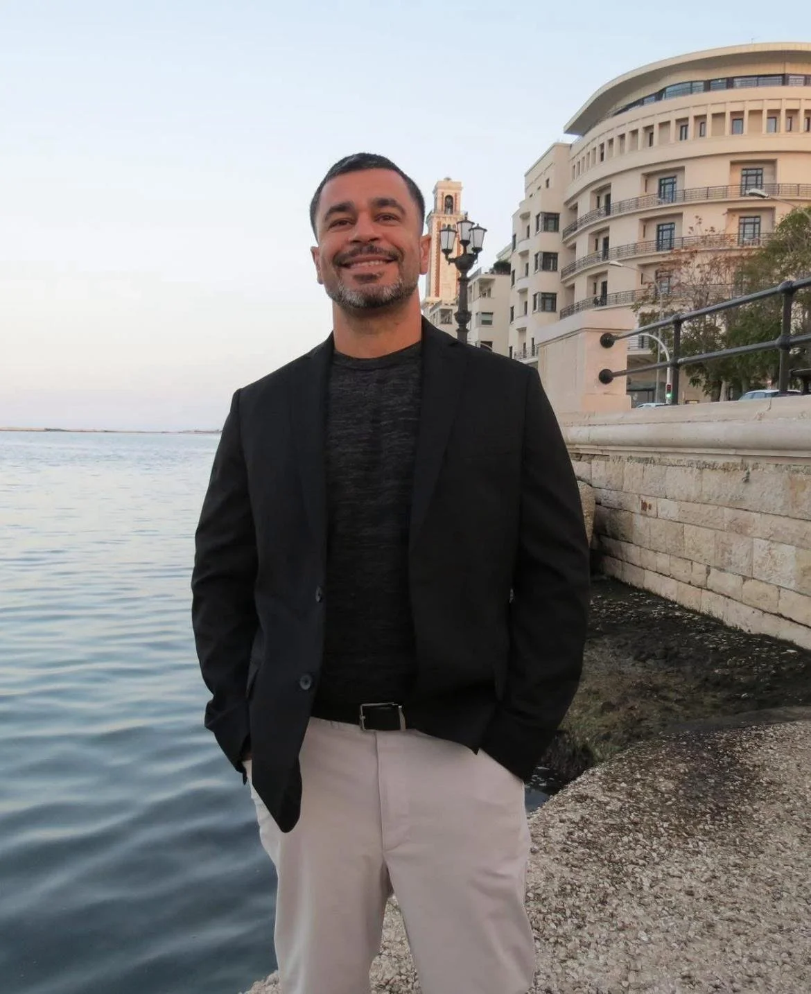 Miguel Ojeda smiling in a blazer beside the water