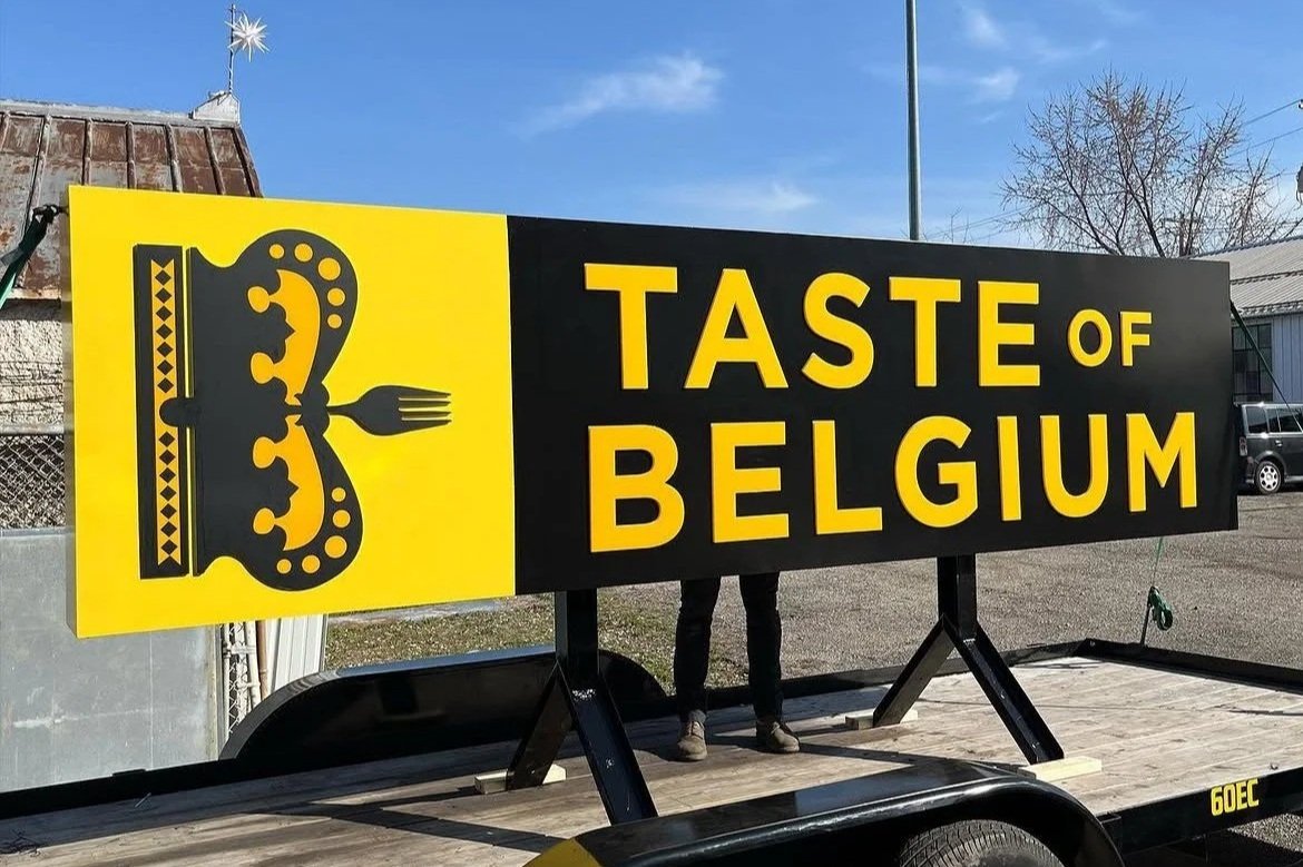 Yellow and black sign reading "Taste of Belgium" sits on a trailer outdoors. Sign created by Brite Line Signs in Columbus, Ohio