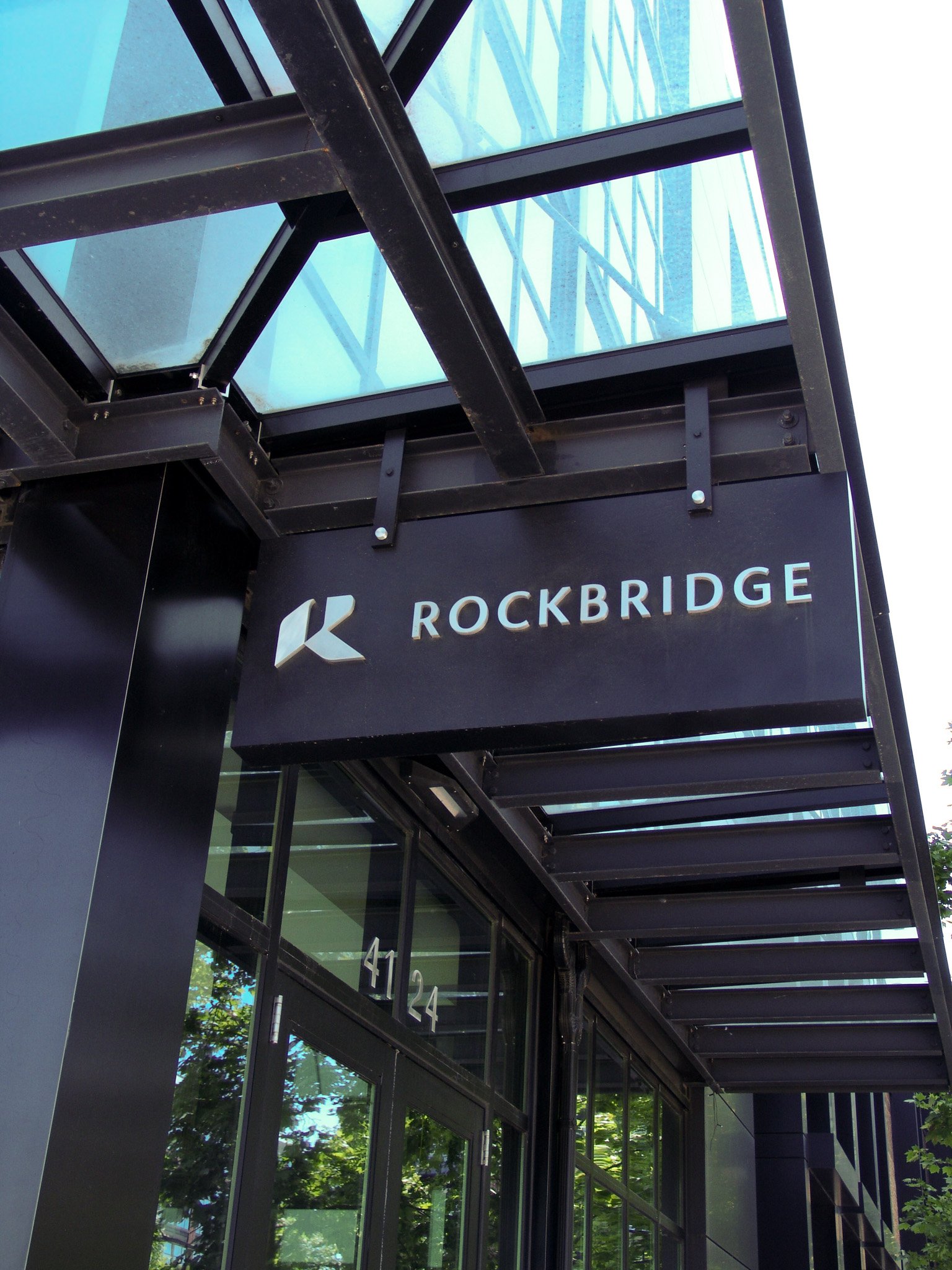 Hanging black sign reading "Rockbridge" on glass overhang, created by Brite Line Signs in Columbus, Ohio