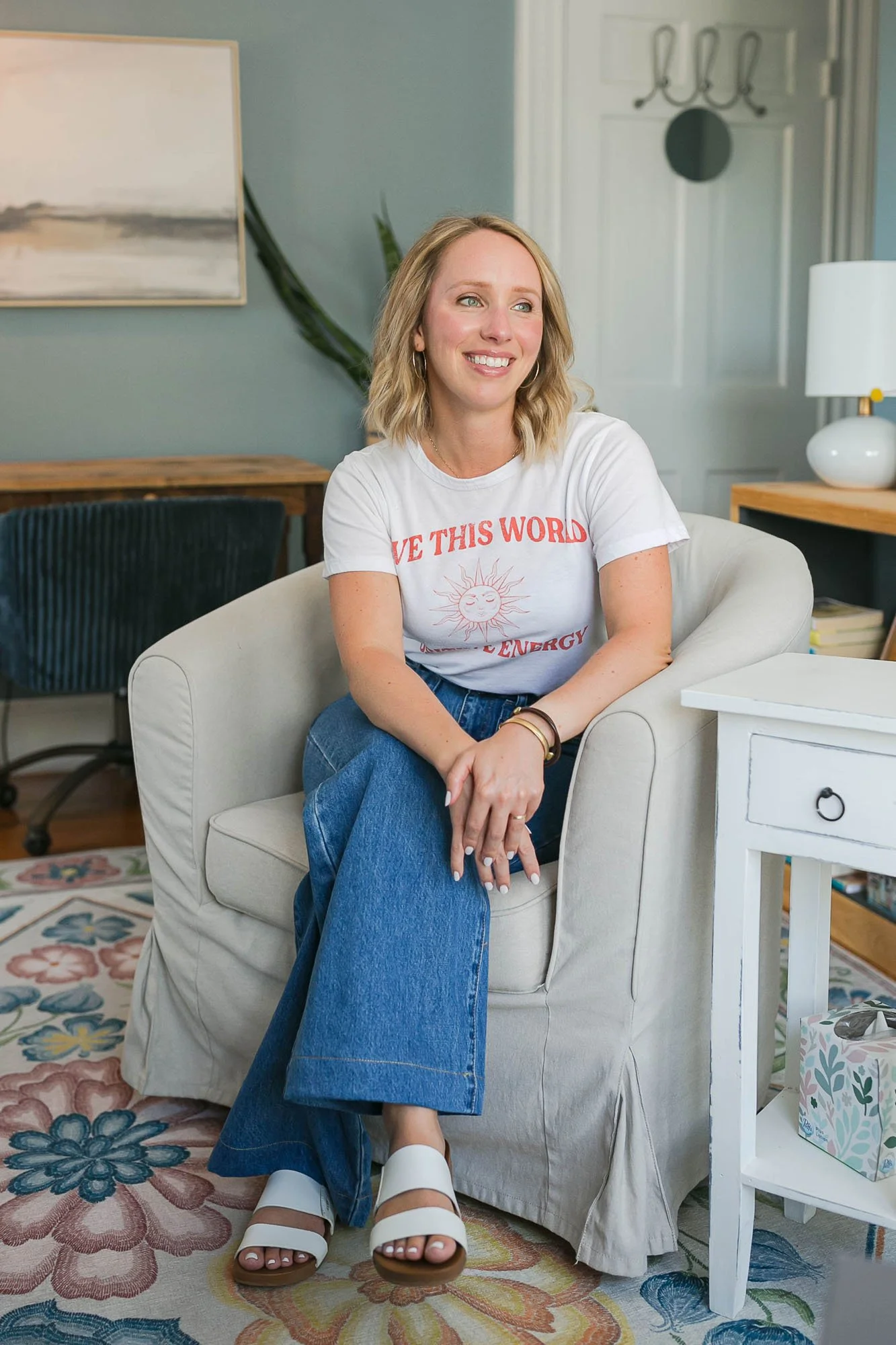 Carli Genet sitting in her office in jeans & t-shirt and birkenstocks
