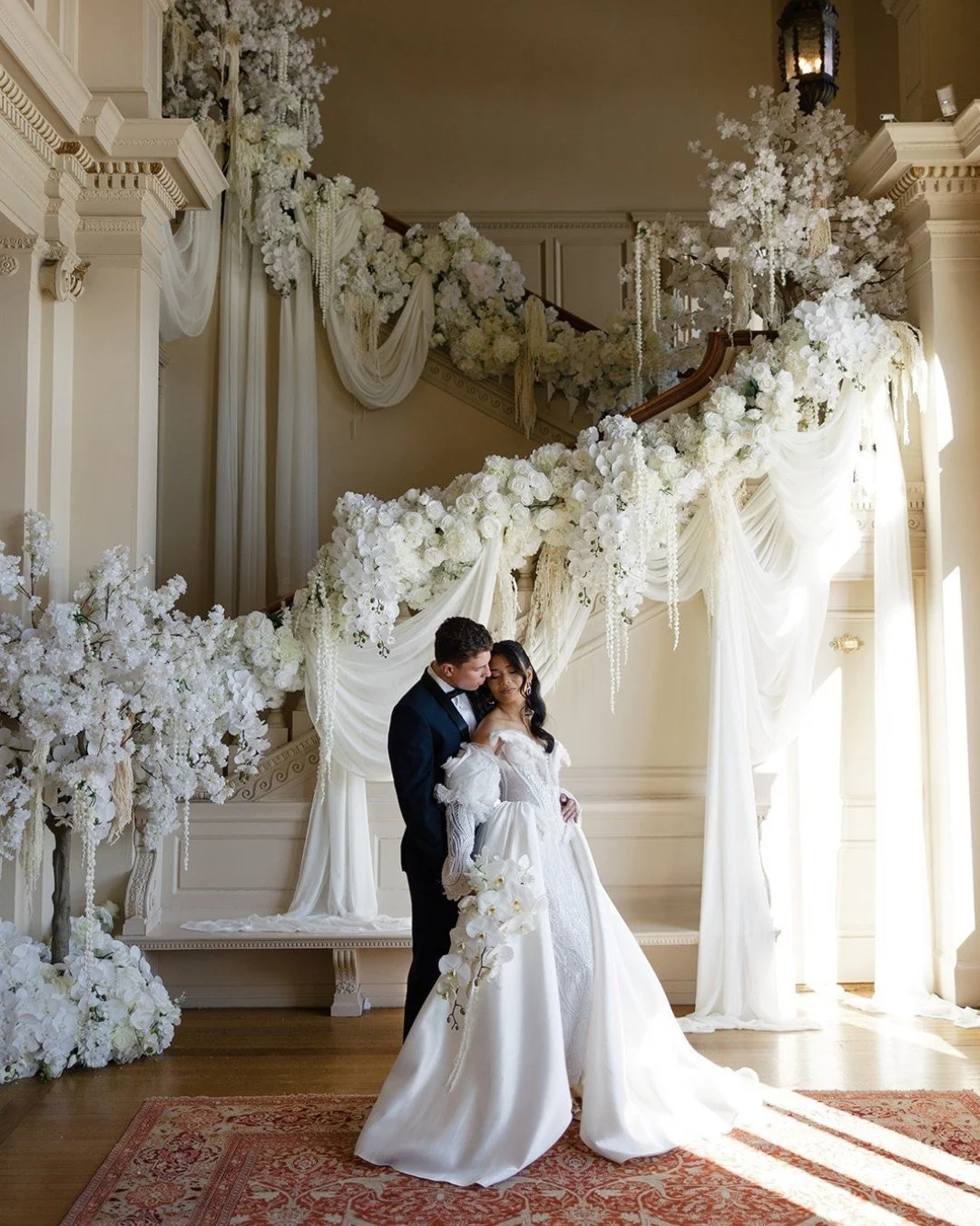 A grand staircase reimagined with cascading drapery and lush white florals, creating movement, depth, and an unmistakable sense of romance. From the delicate placement of each bloom to the way the fabric falls so effortlessly, every detail was design