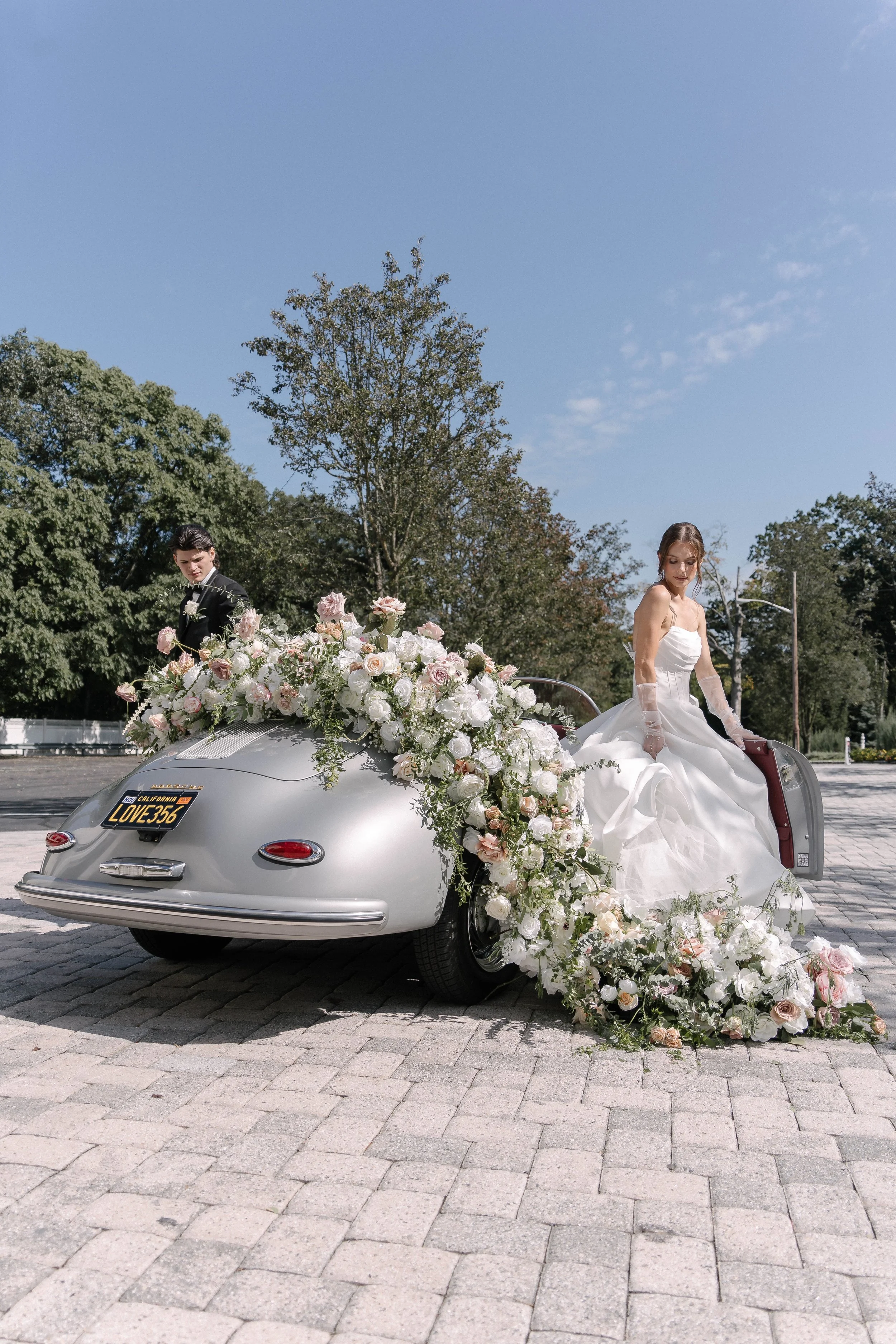 Newly wed couple coming out of a car with flowers