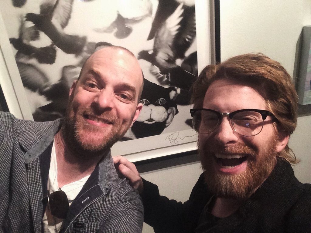 Photographer Rich Hardcastle and actor Seth Green in front of Hardcastle’s work featuring Ricky Gervais