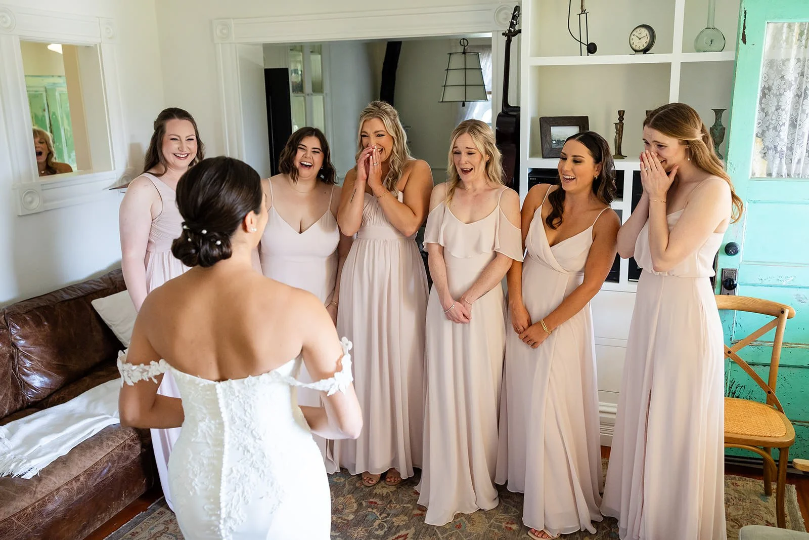 Bridesmaids reacting with joy as bride reveals her dress inside the Flying Caballos Farmhouse, San Luis Obispo