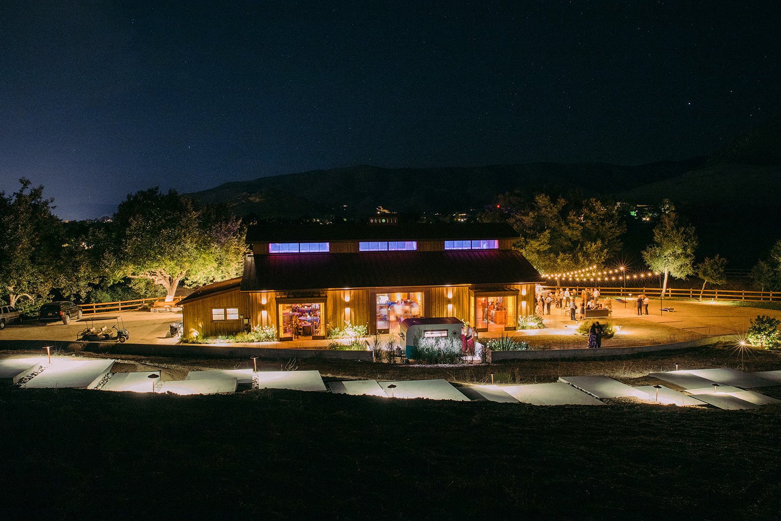 Flying Caballos Ranch Barn lit up at night with string lights and stars overhead, aerial wedding photography San Luis Obispo