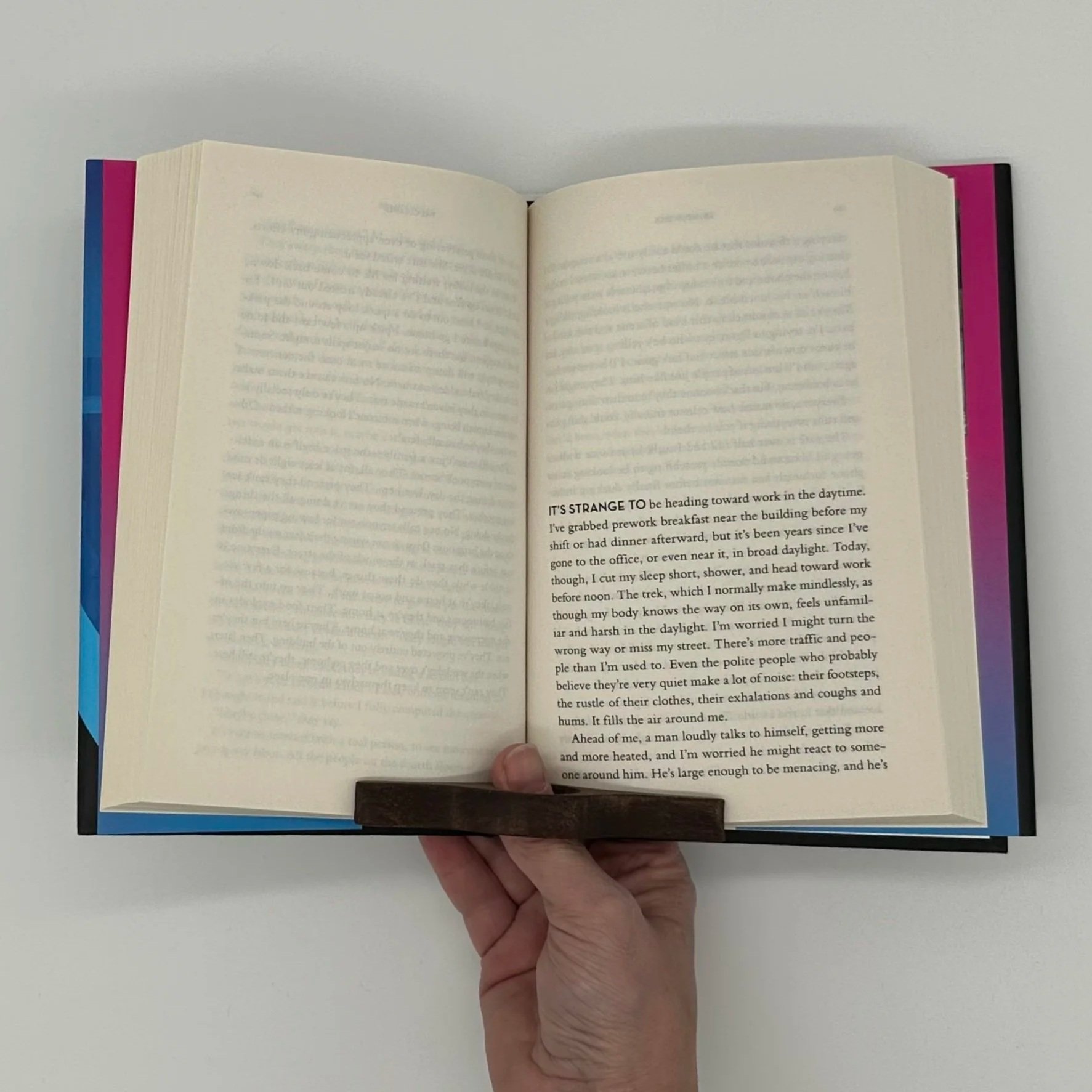 Someone using a wooden holder to keep the pages of a book open.