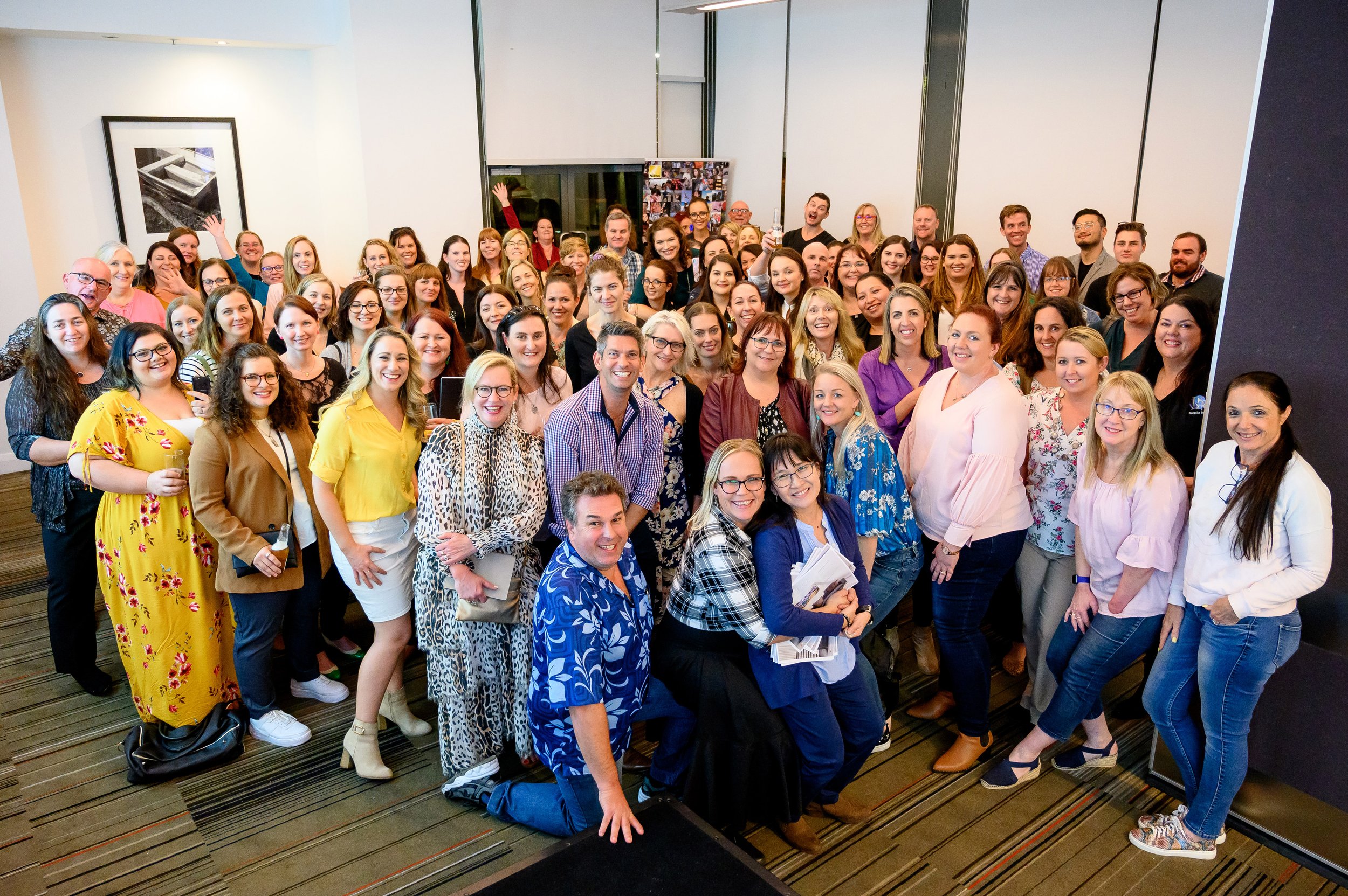 A group of more than 40 people stand together smiling. Mark is a row back from a small group in the front.