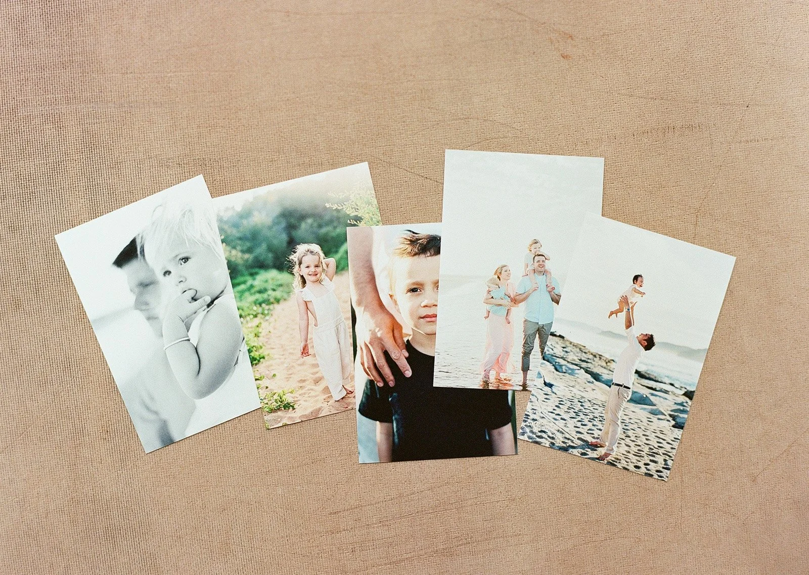 Collection of five printed photographs of a family on a textured beige background at Atkins Photo Lab.