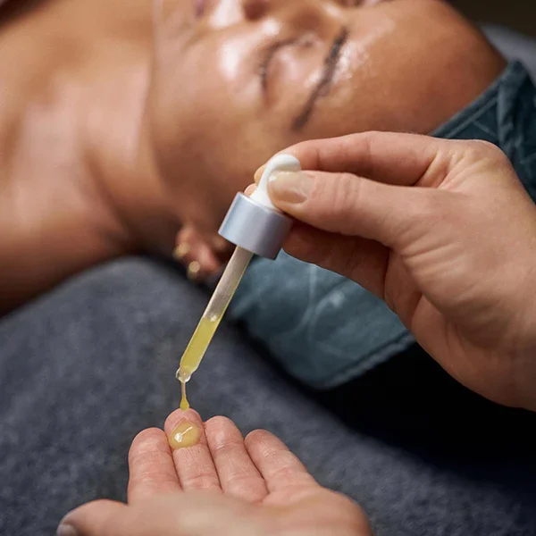 Person receiving a CBD oil tincture dropper under their tongue while lying down.