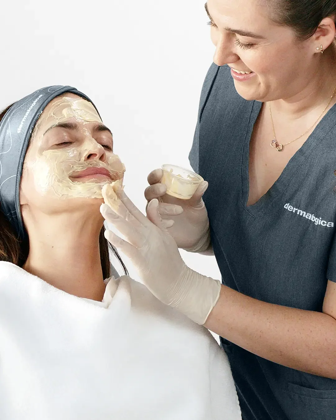 A woman receives a facial treatment from a skincare professional in a clinic setting.