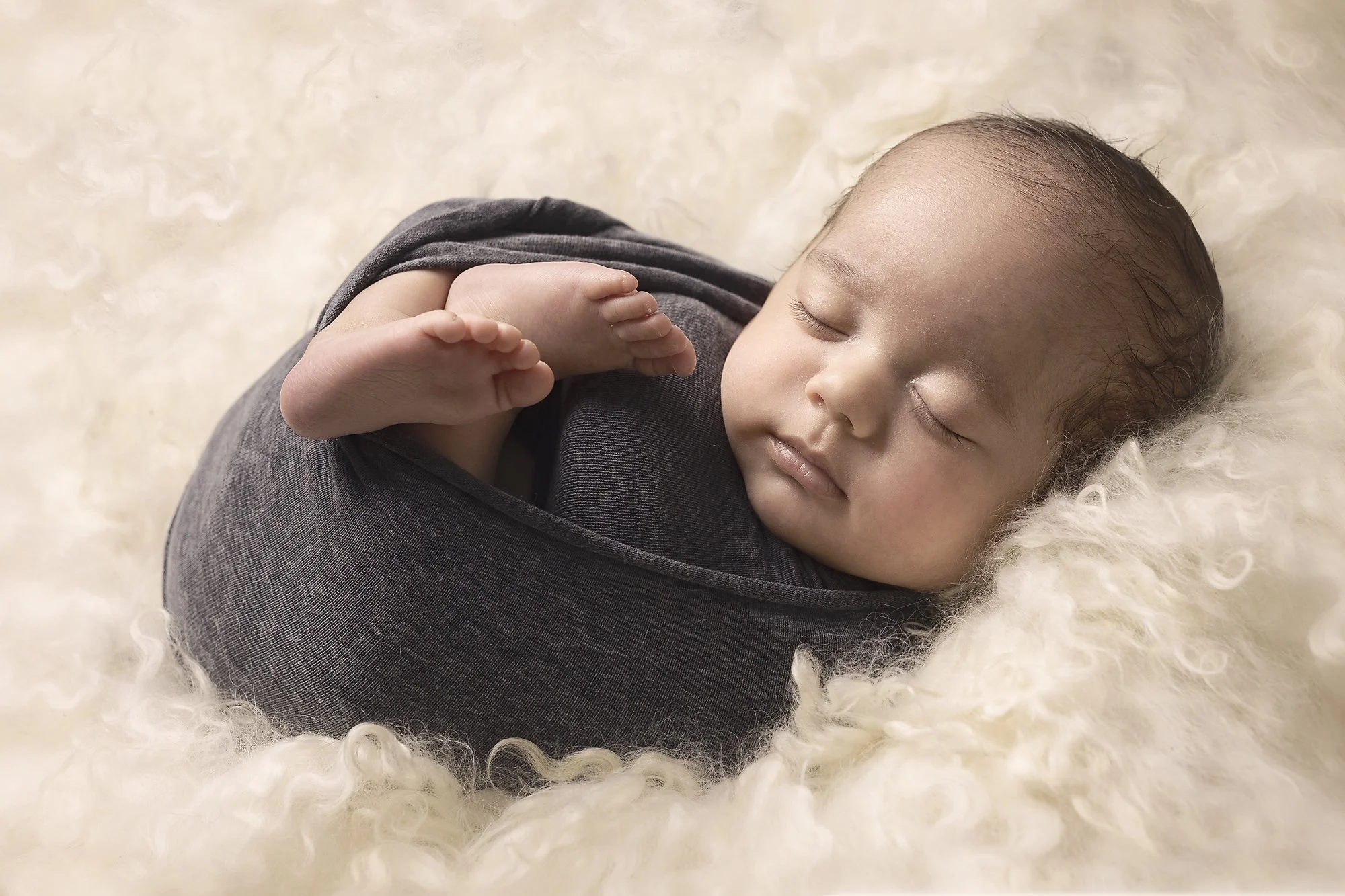 baby boy wrappe din blue asleep on cream curls, newborn family photoshoot, western sydney