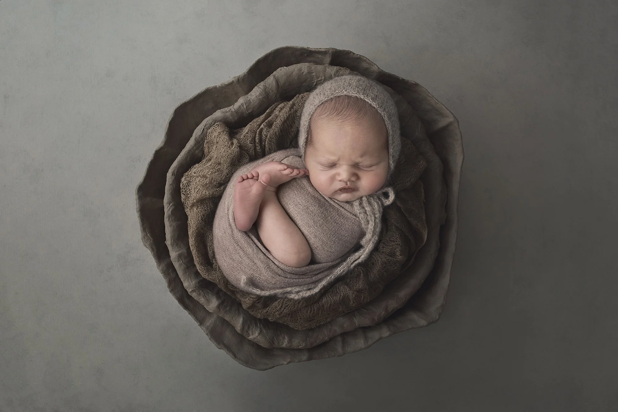 newborn baby boy wrapped in brown in a bowl with bonnet asleep penrith western sydney photographer