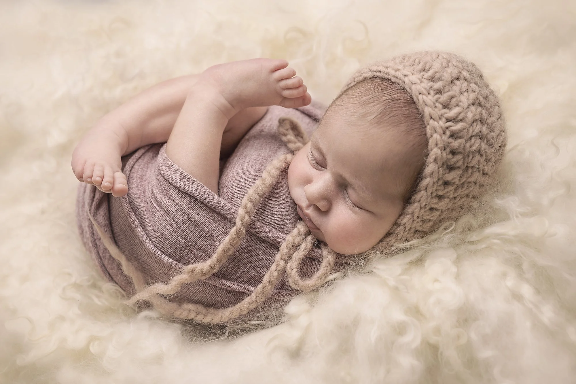 newborn baby girl photographed asleep in pink bonnet and wrapped on cream curls penrith blue mountains western sydney hills district